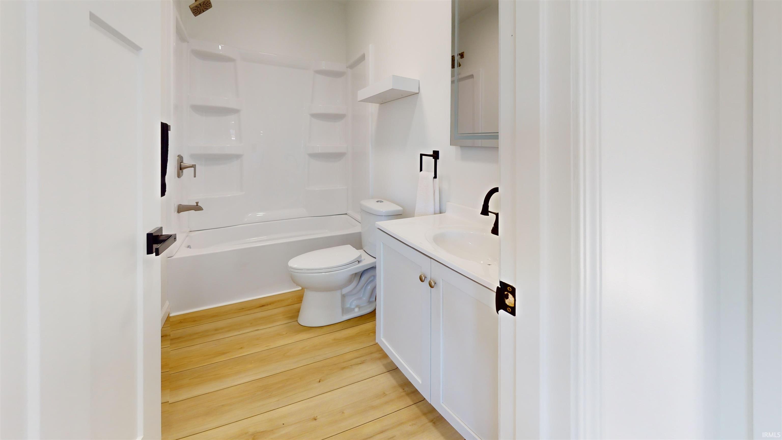 Bathroom with vanity, light wood-style floors, and shower / washtub combination
