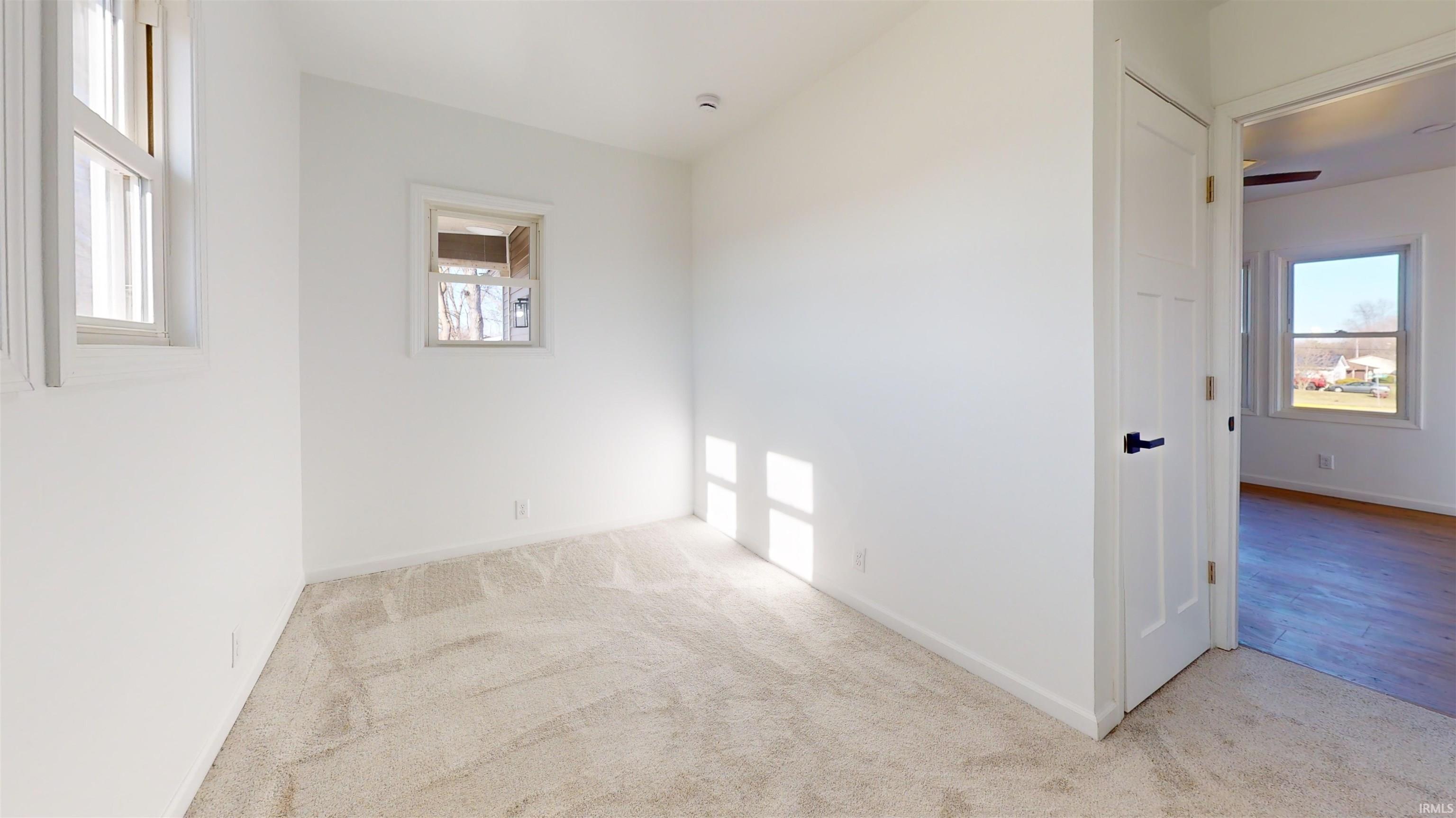 Empty room with light colored carpet and ceiling fan