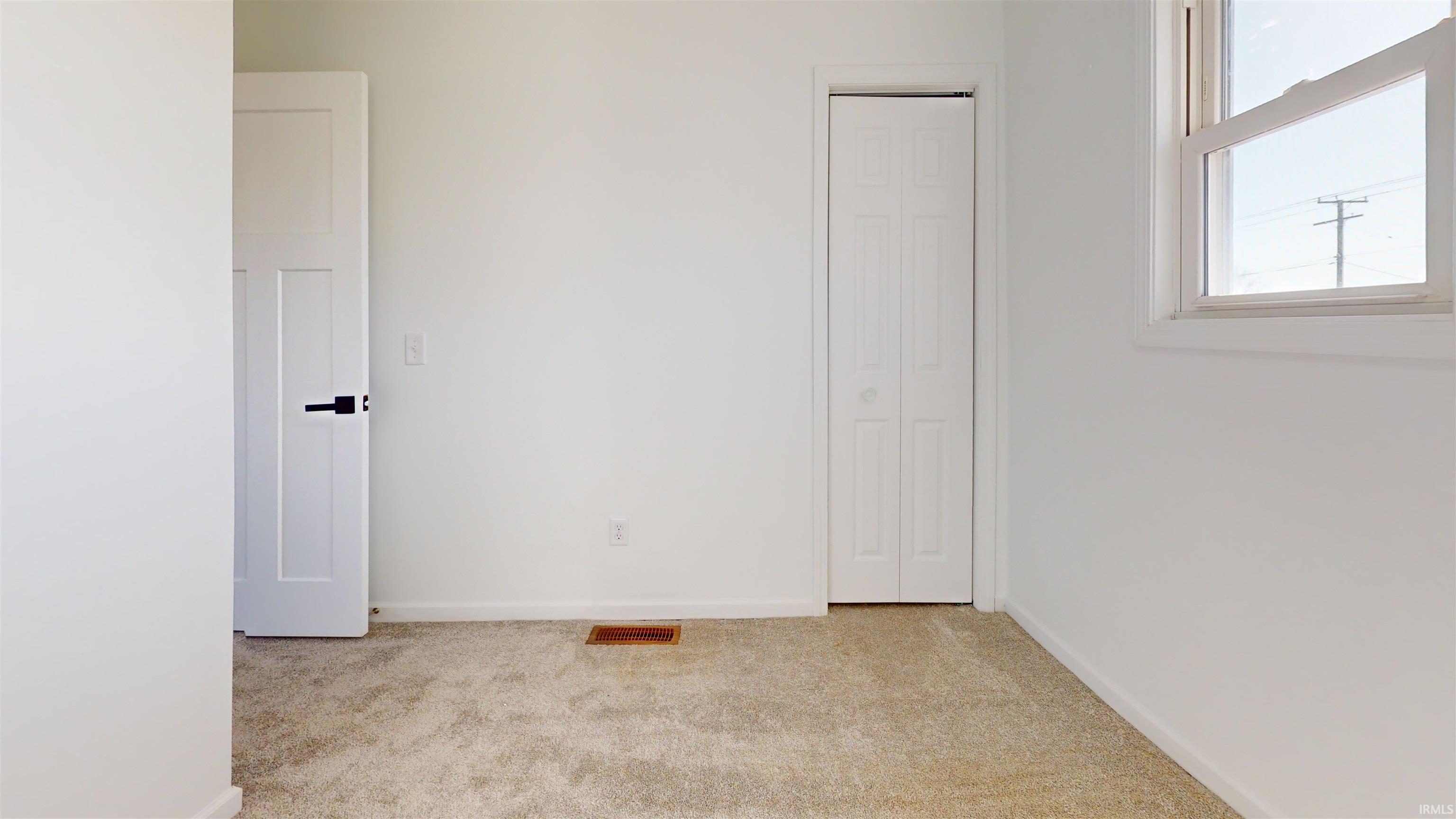 Unfurnished bedroom with light carpet and baseboards