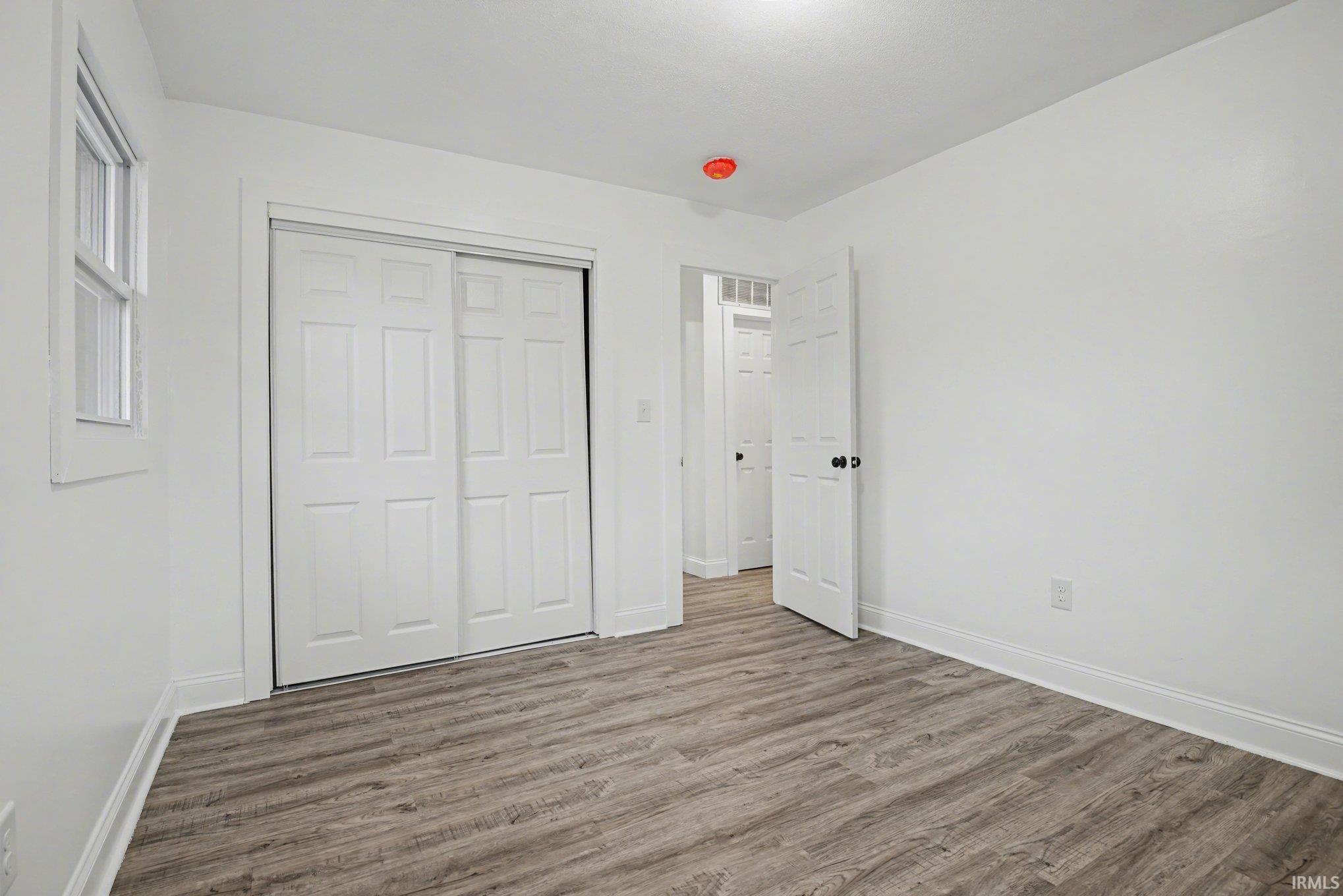 Unfurnished bedroom with wood finished floors and a closet