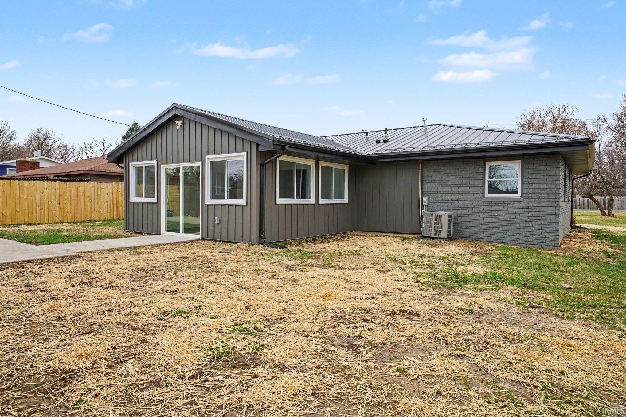 Back of property with a metal roof and brick siding