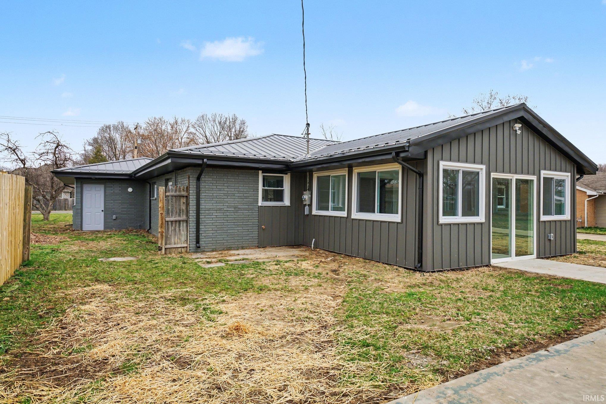 View of side of property with a metal roof and brick siding