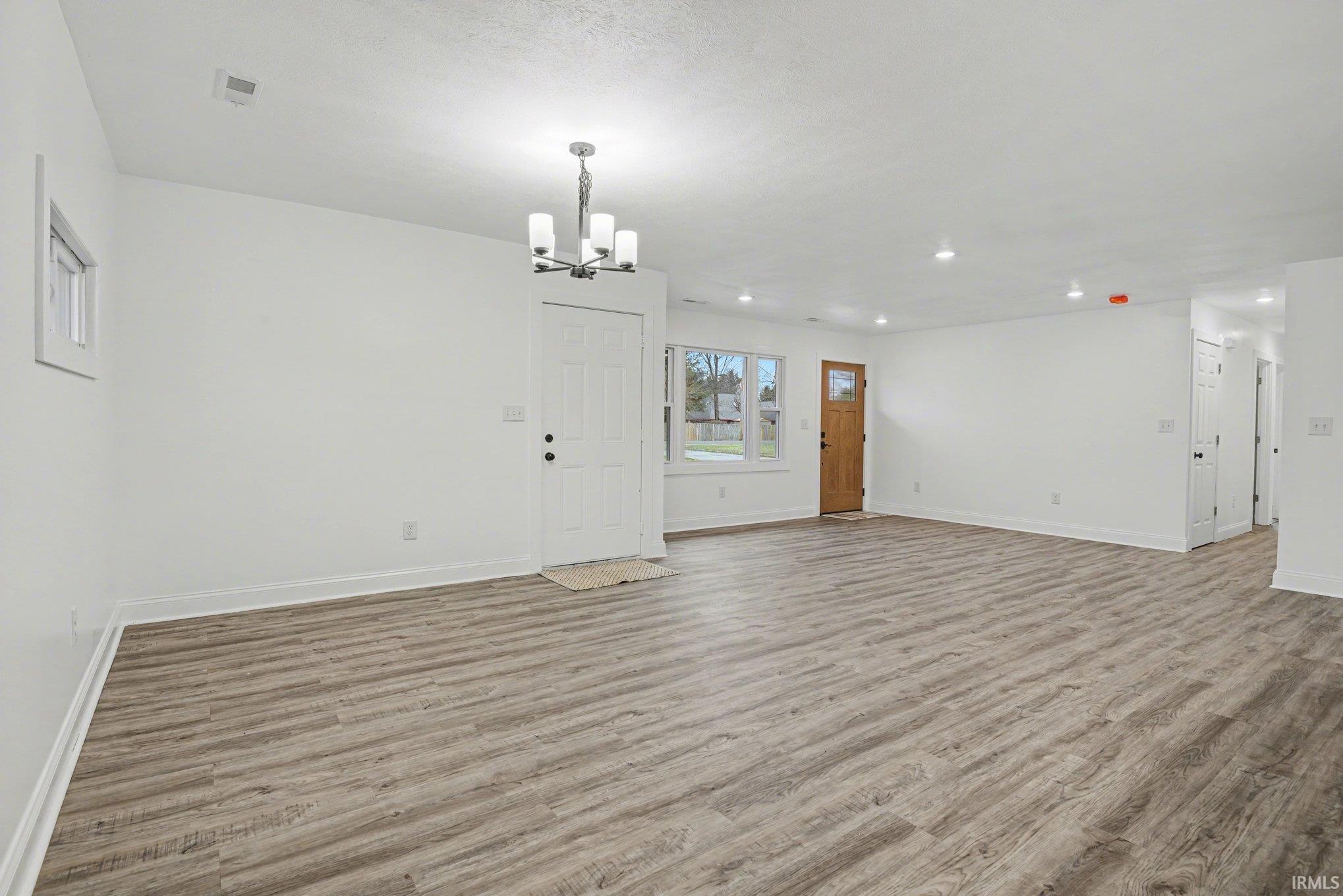 Unfurnished living room with light wood-style flooring and a chandelier