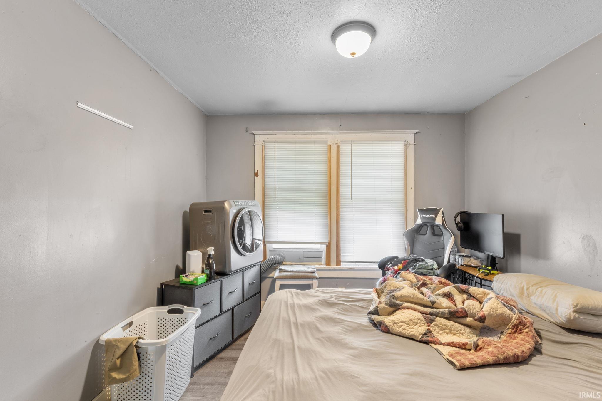 Bedroom with washer / clothes dryer, a textured ceiling, and light wood-style floors