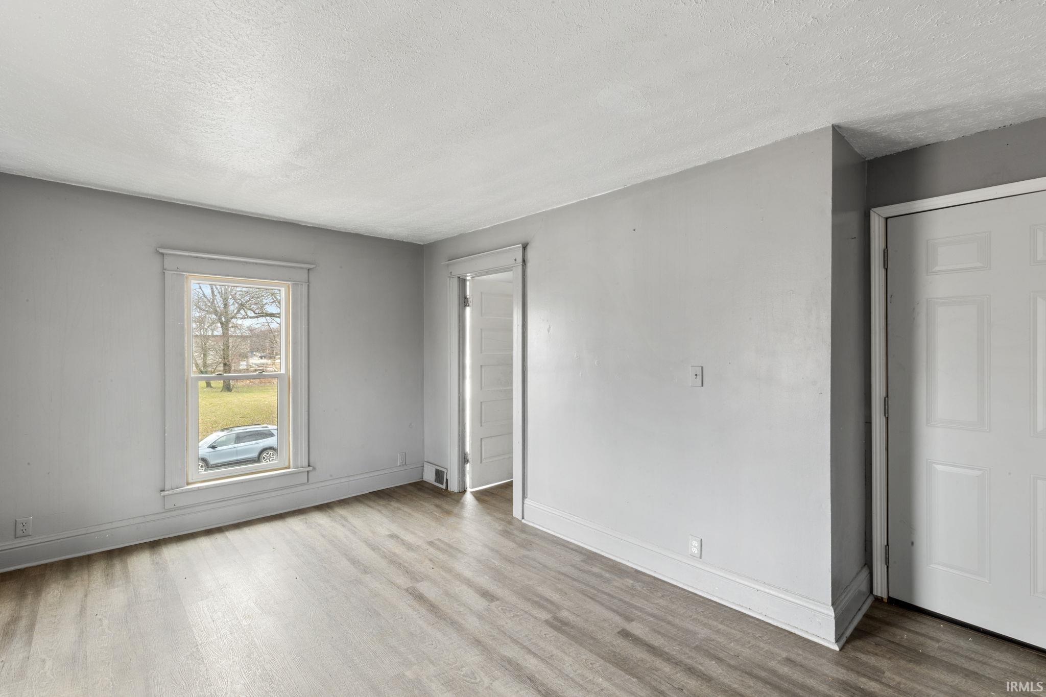 Unfurnished bedroom with light wood-type flooring and a textured ceiling