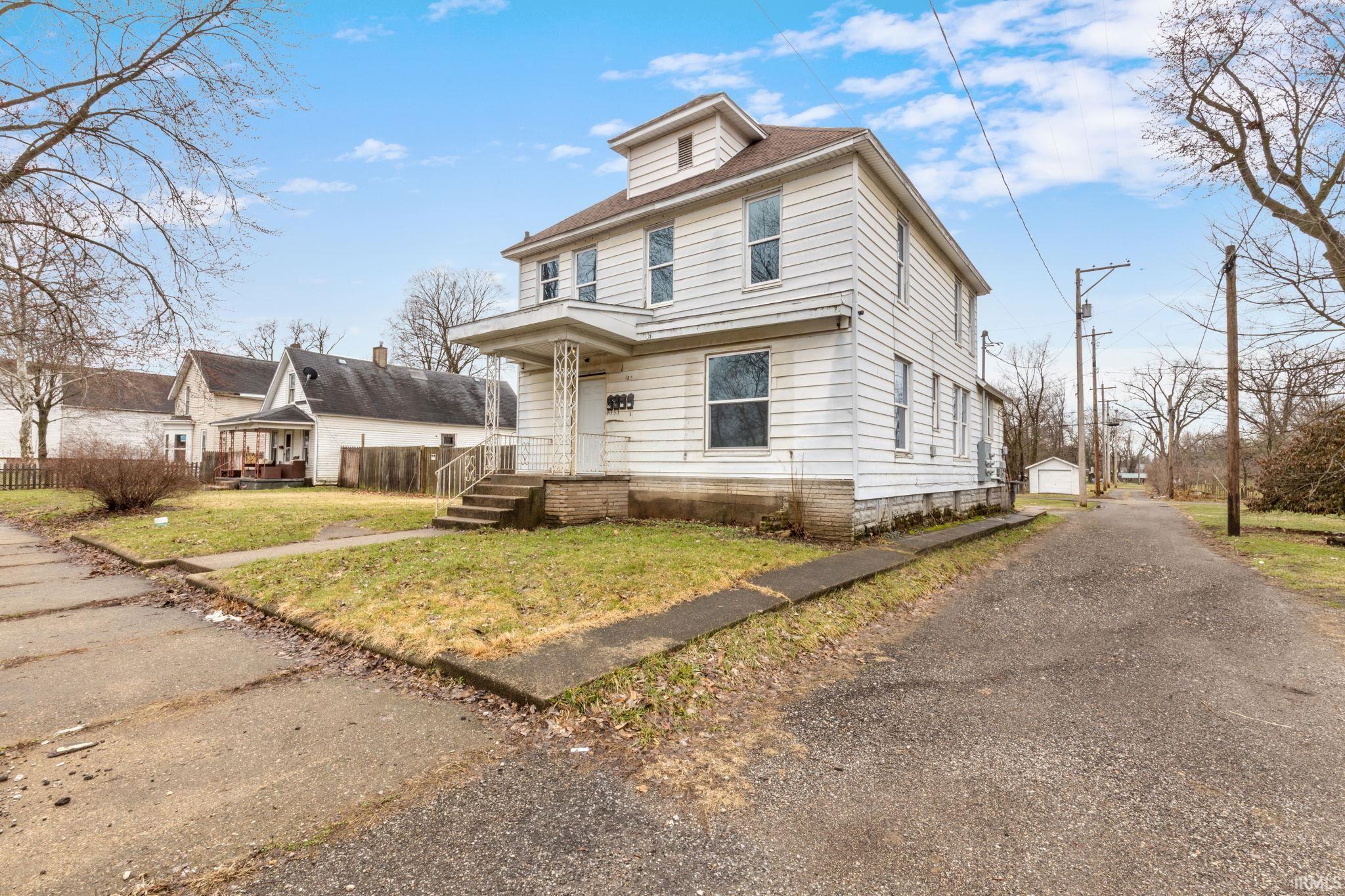 American foursquare style home with a front lawn, a detached garage, an outdoor structure, and roof with shingles