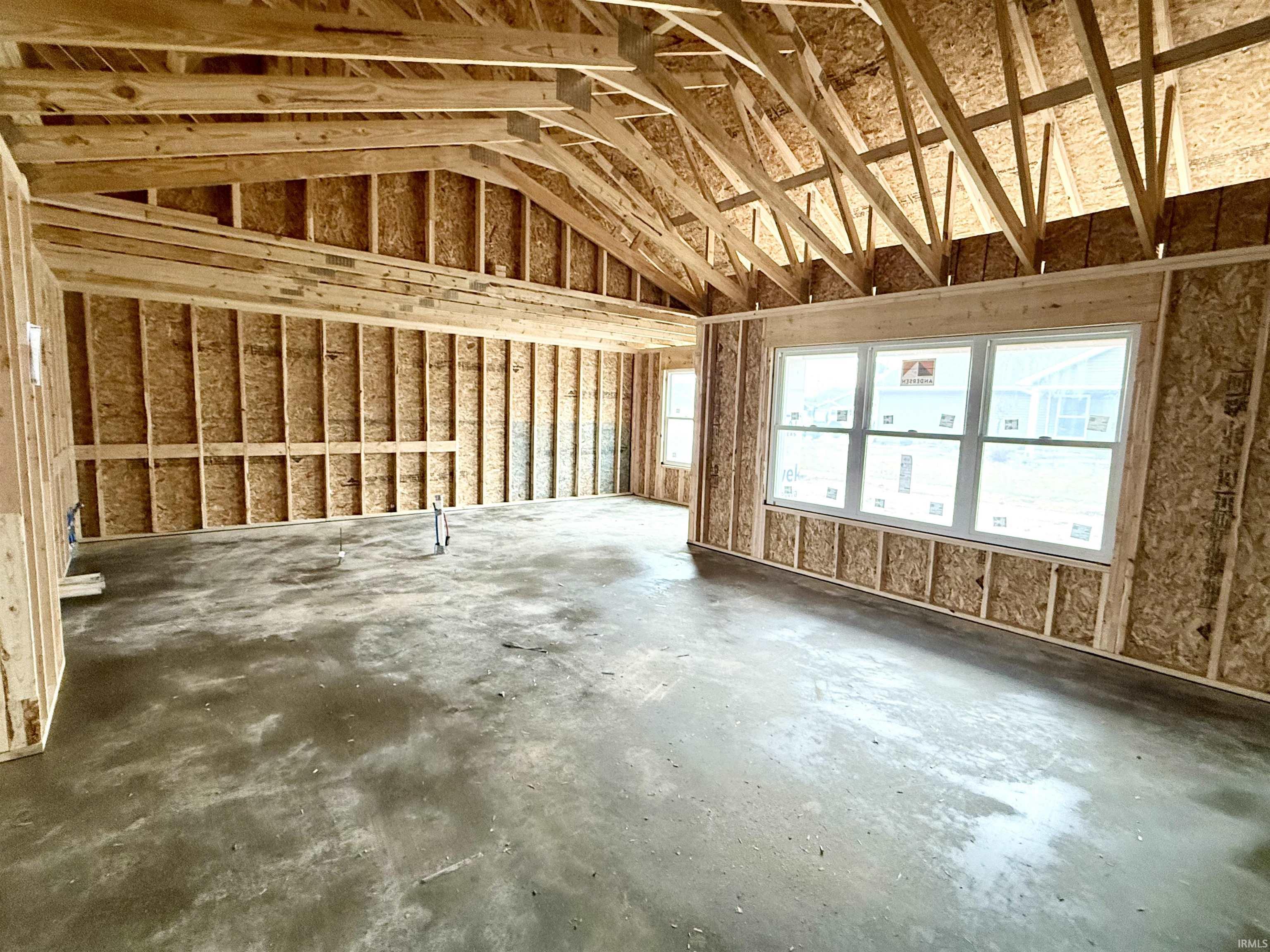 Misc room featuring unfinished concrete floors and lofted ceiling