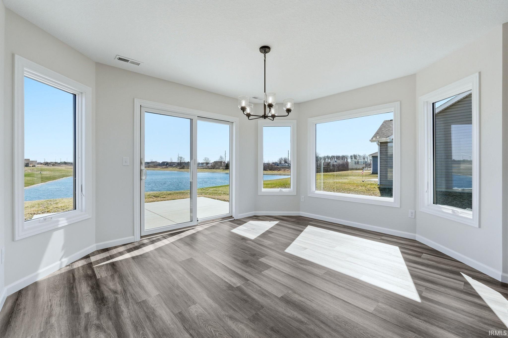 Unfurnished dining area featuring a water view, a chandelier, and dark wood-type flooring