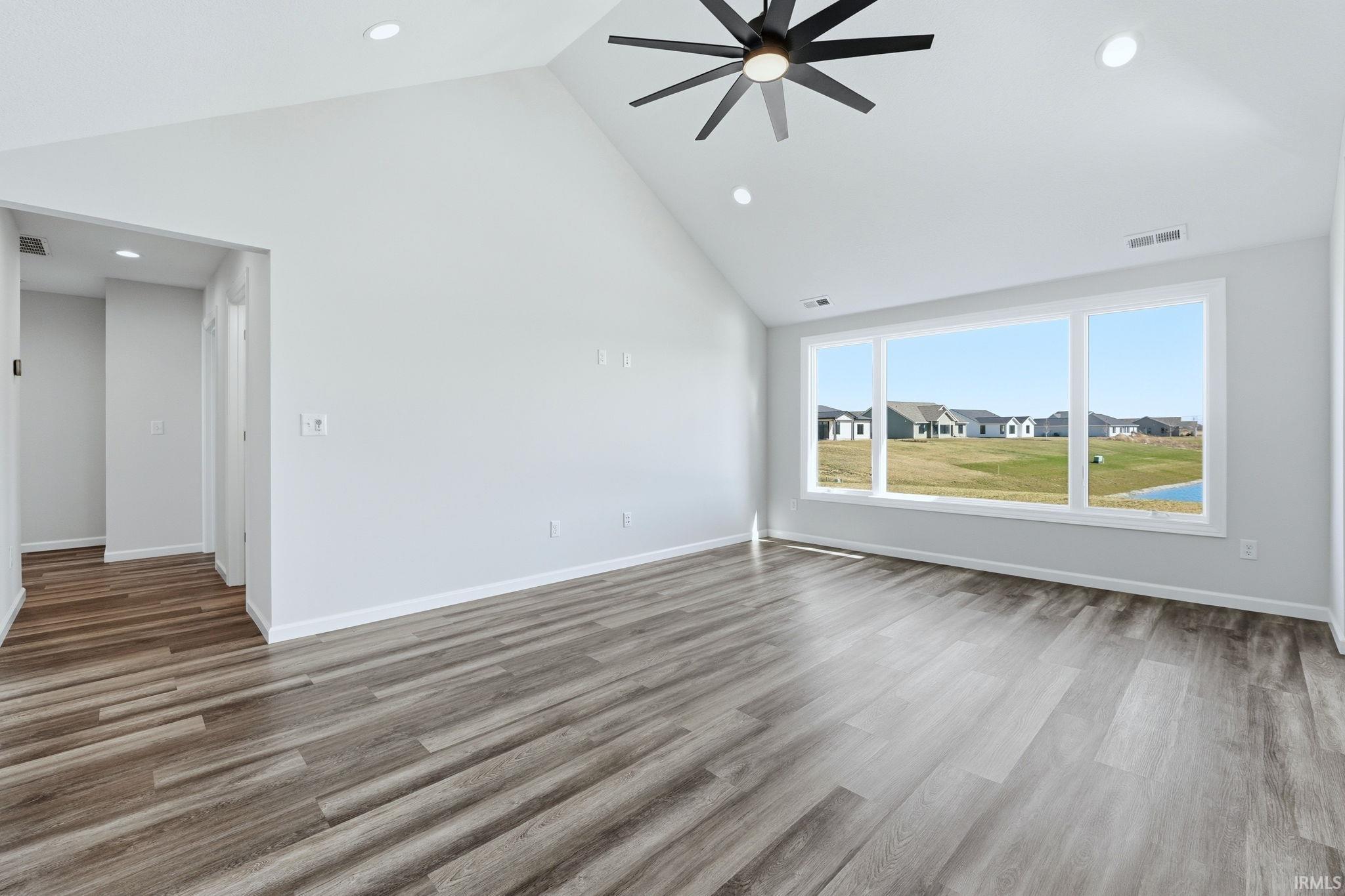 Unfurnished living room with a high ceiling, a ceiling fan, light wood-type flooring, a residential view, and recessed lighting