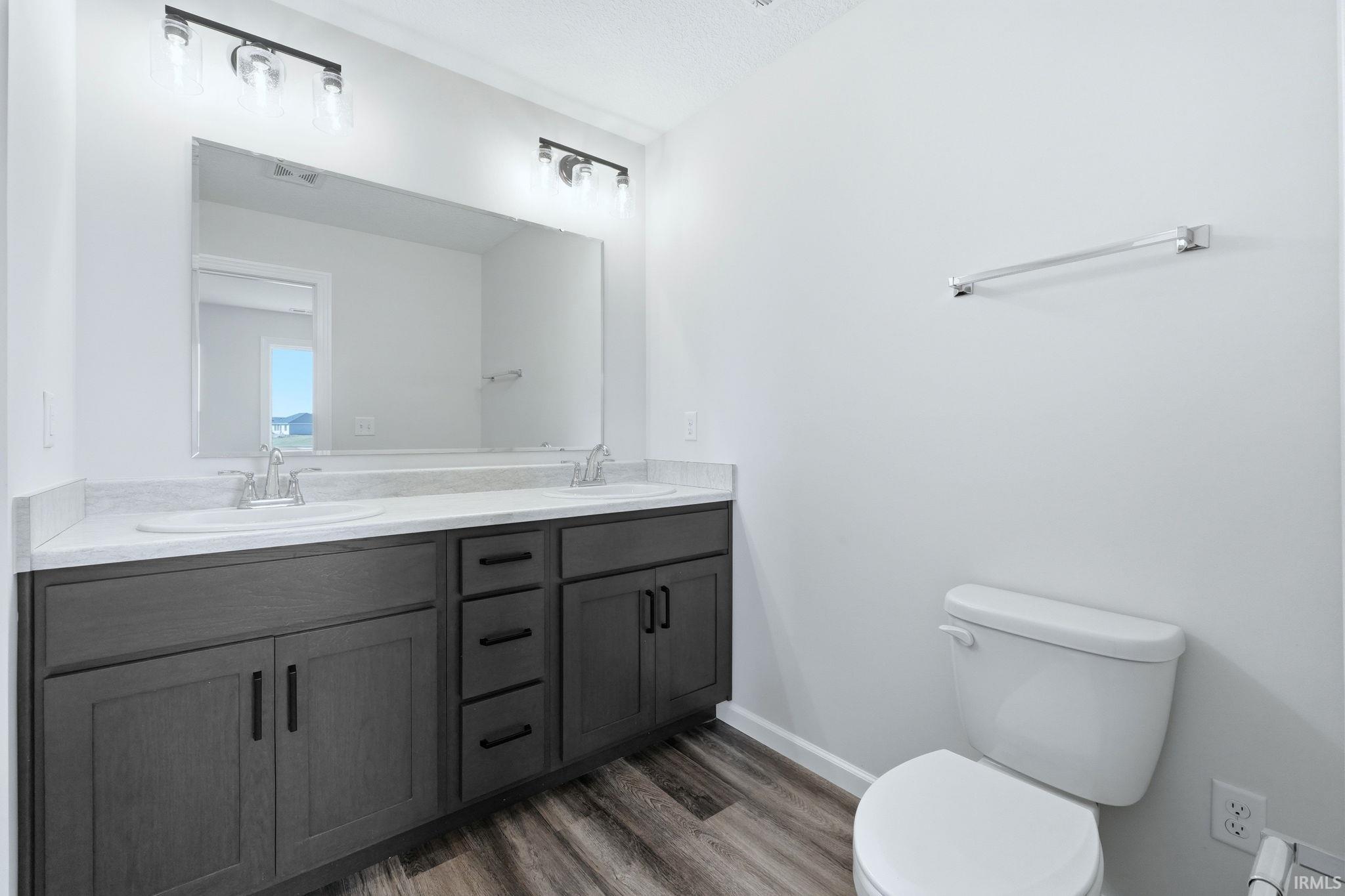 Full bath featuring double vanity and dark wood-style floors