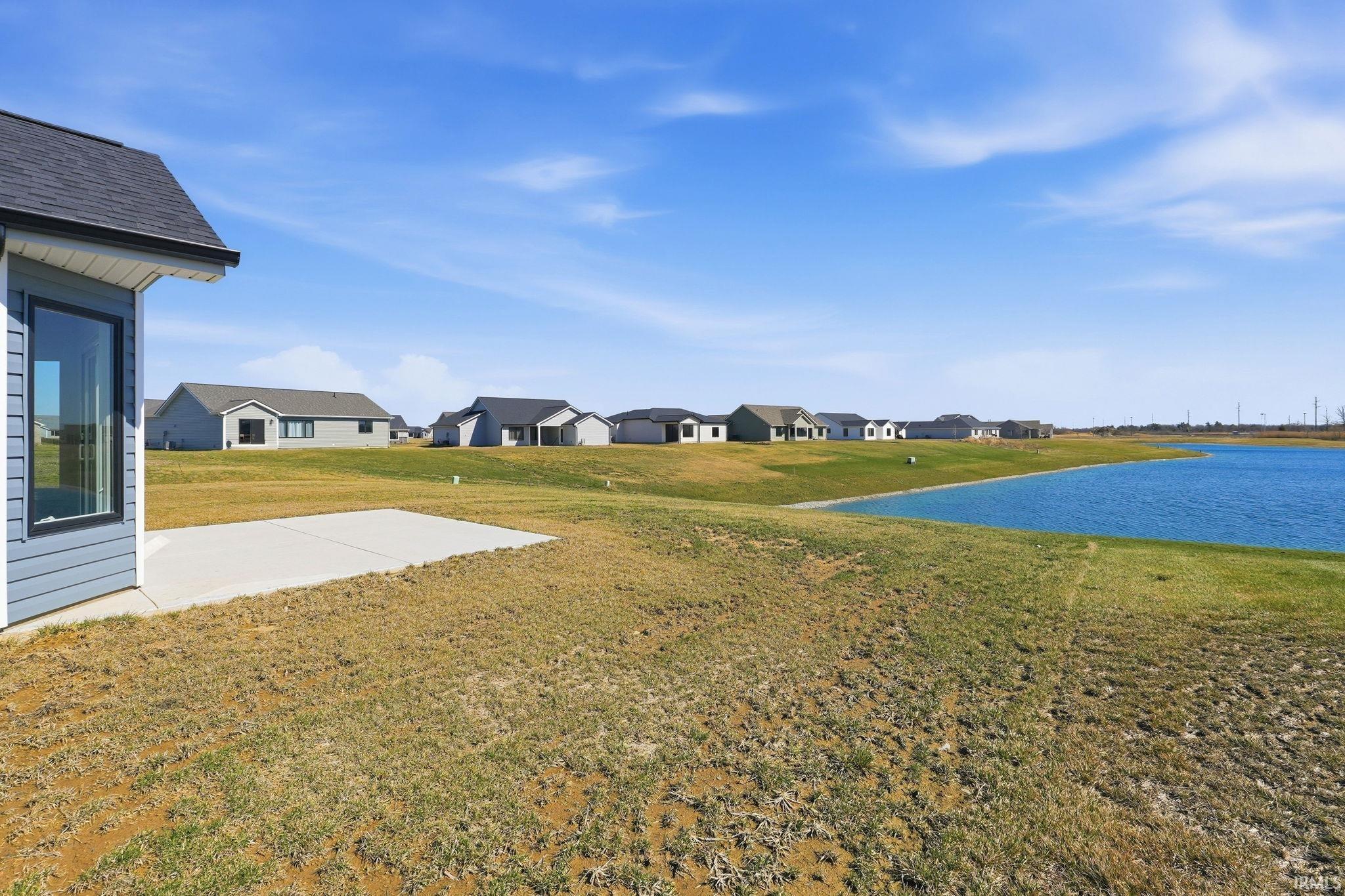View of grassy yard with a residential view, a water view, and a patio