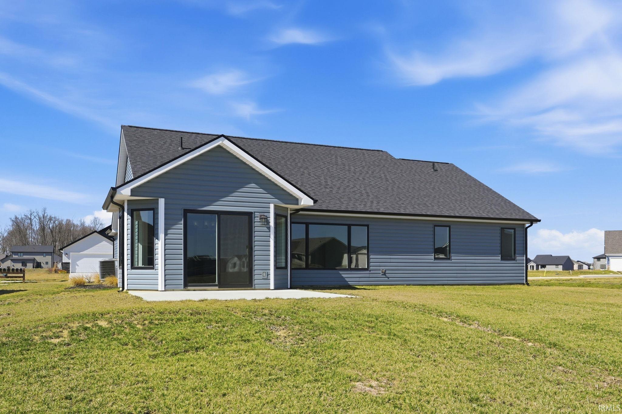 Back of house featuring a lawn and roof with shingles