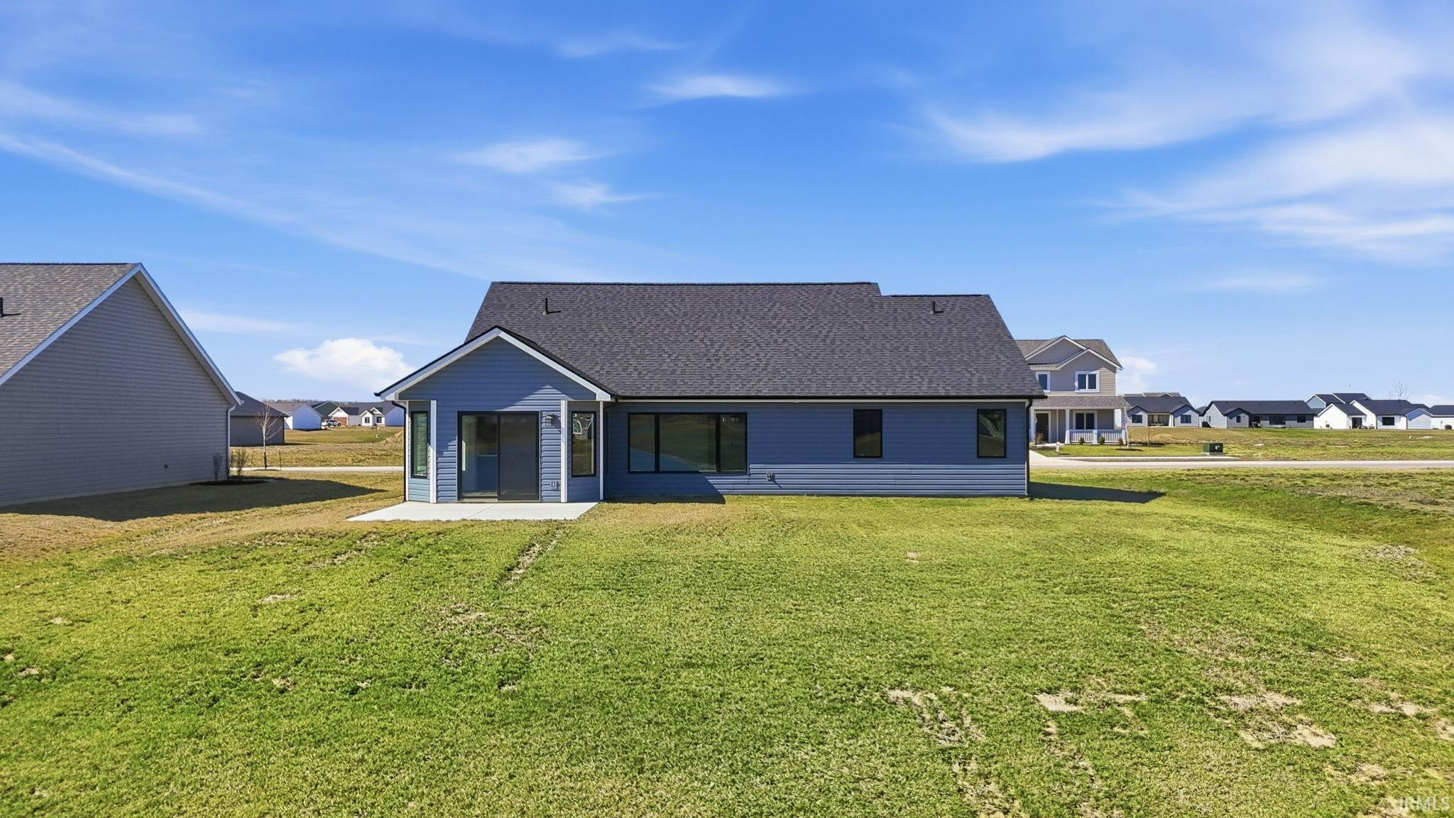 Back of property featuring a residential view, roof with shingles, a yard, and a patio area