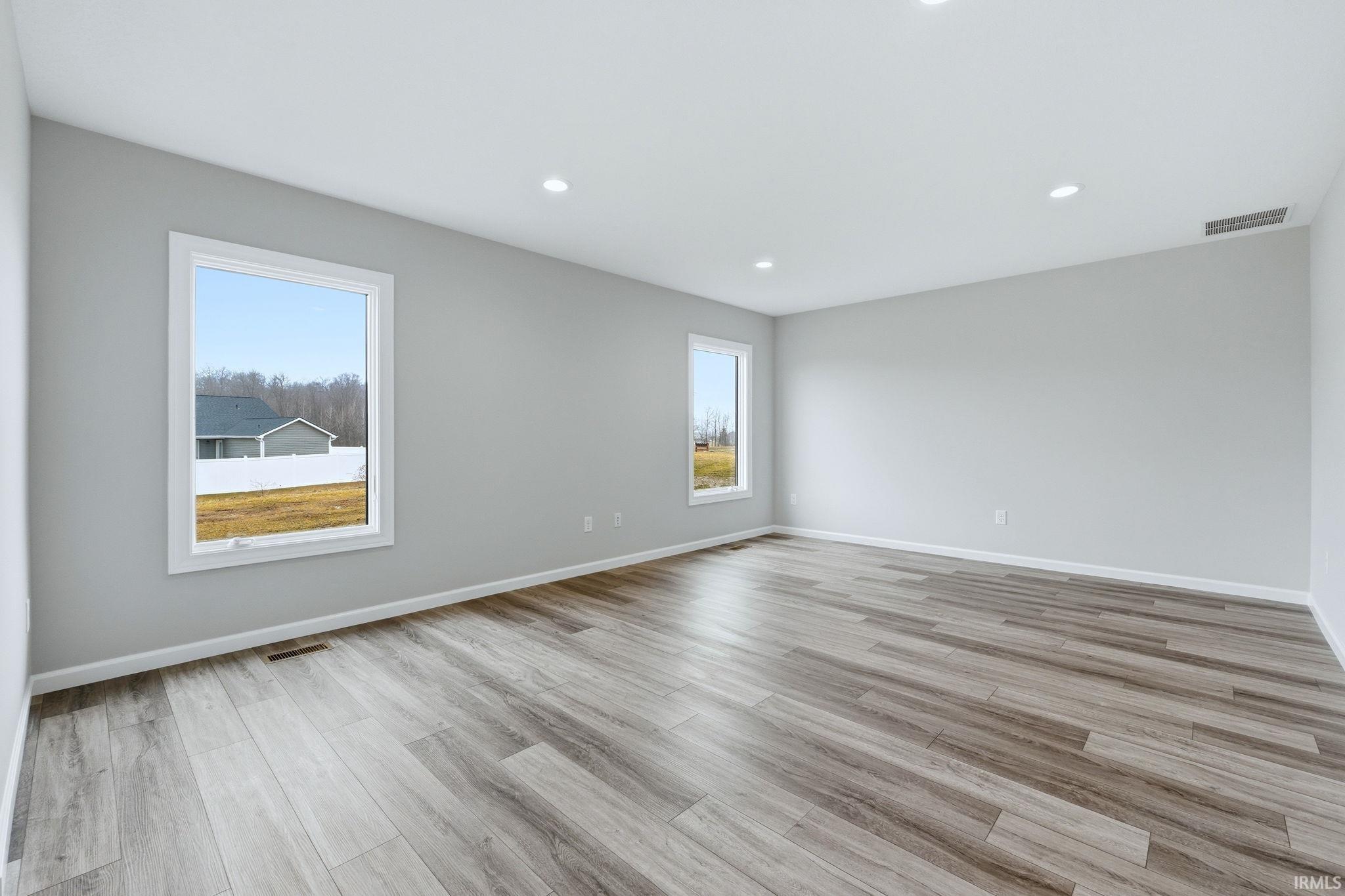 Empty room with light wood finished floors, healthy amount of natural light, and recessed lighting