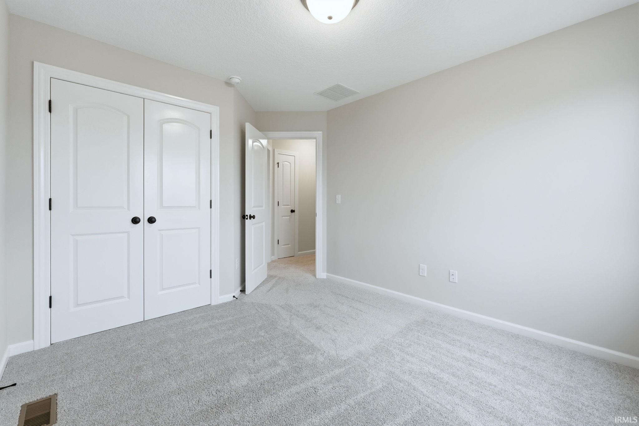 Unfurnished bedroom featuring light colored carpet and a closet