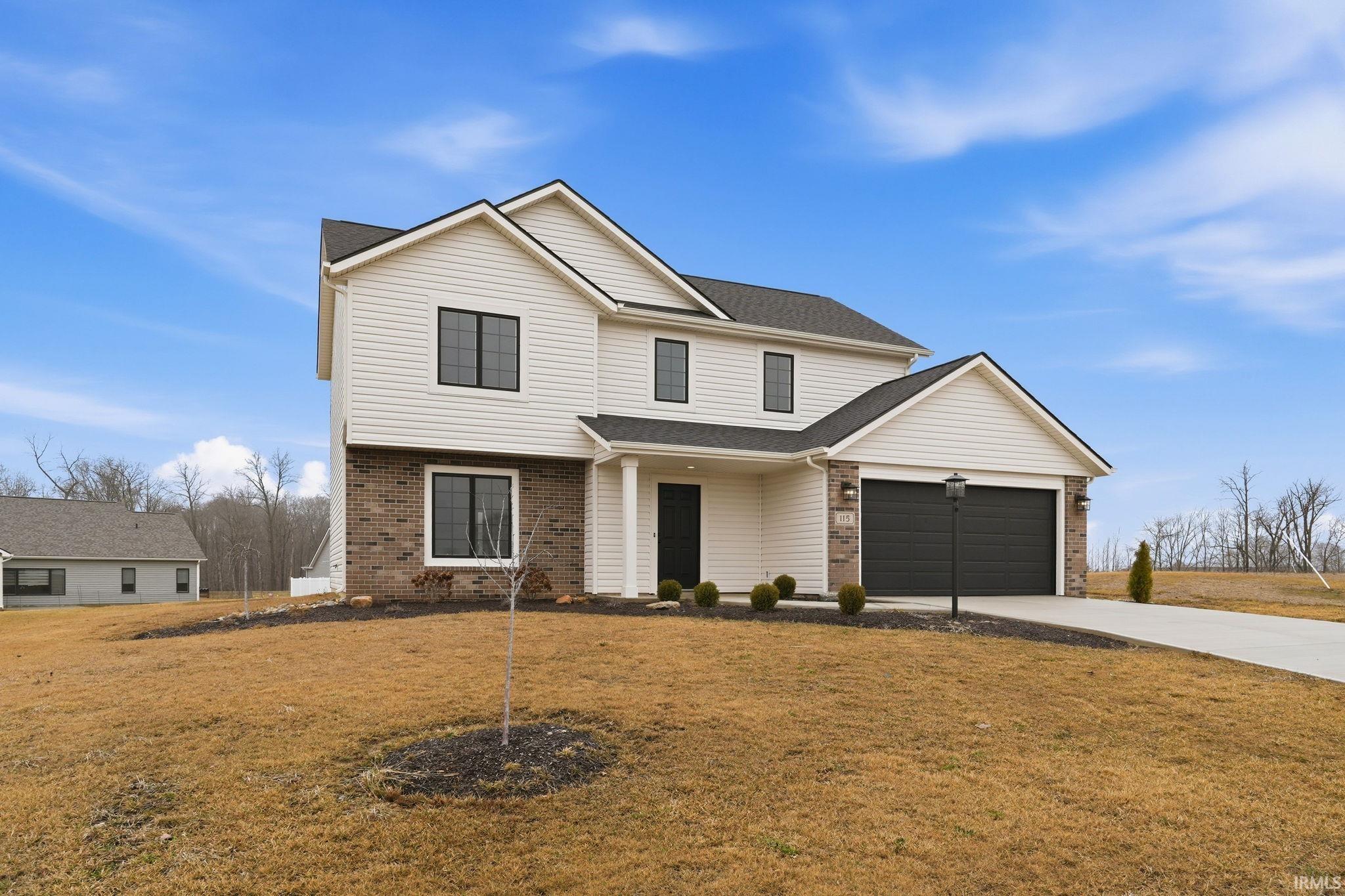 Traditional-style house with brick siding, a front lawn, concrete driveway, a garage, and roof with shingles
