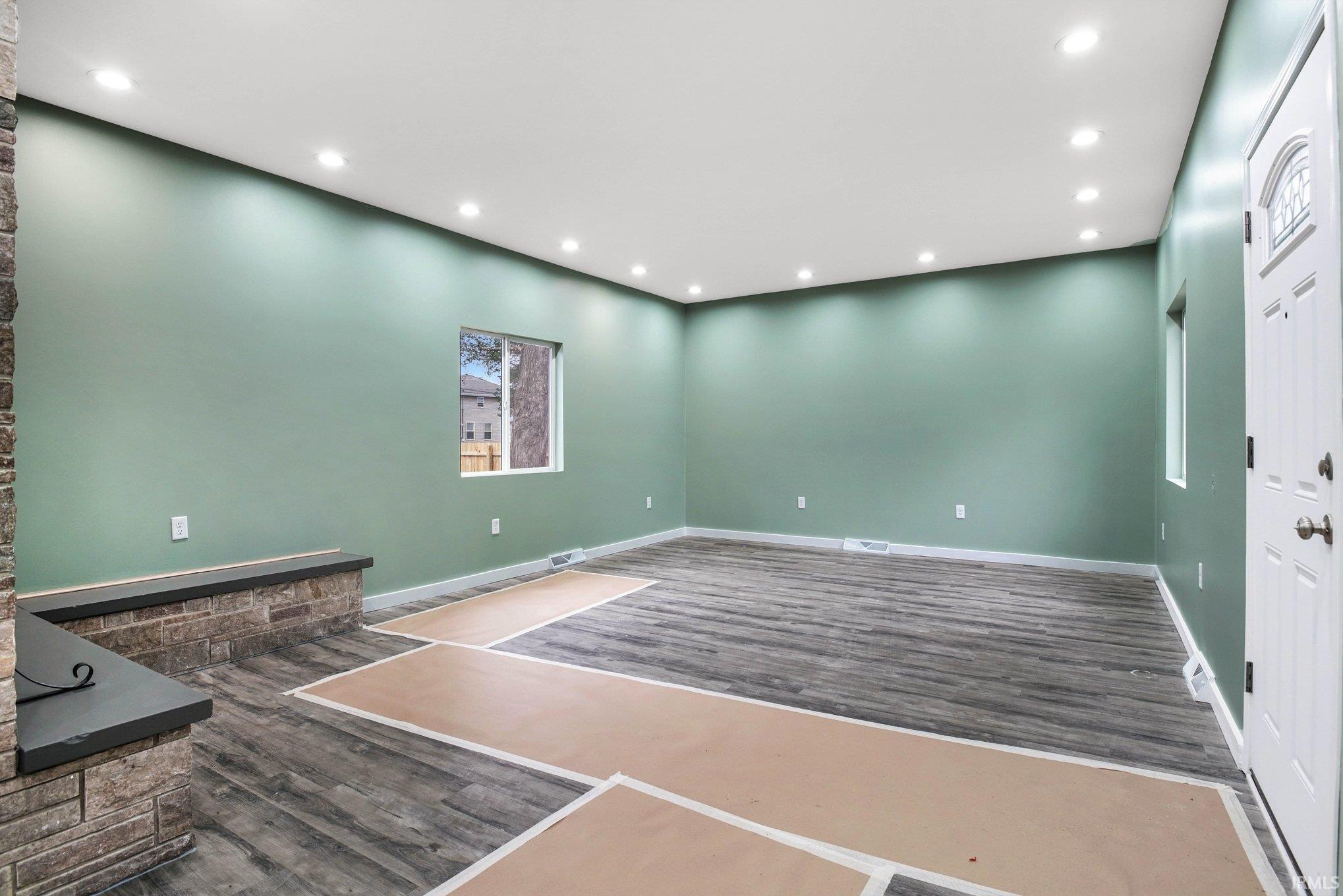 Unfurnished living room with dark wood-style flooring and recessed lighting