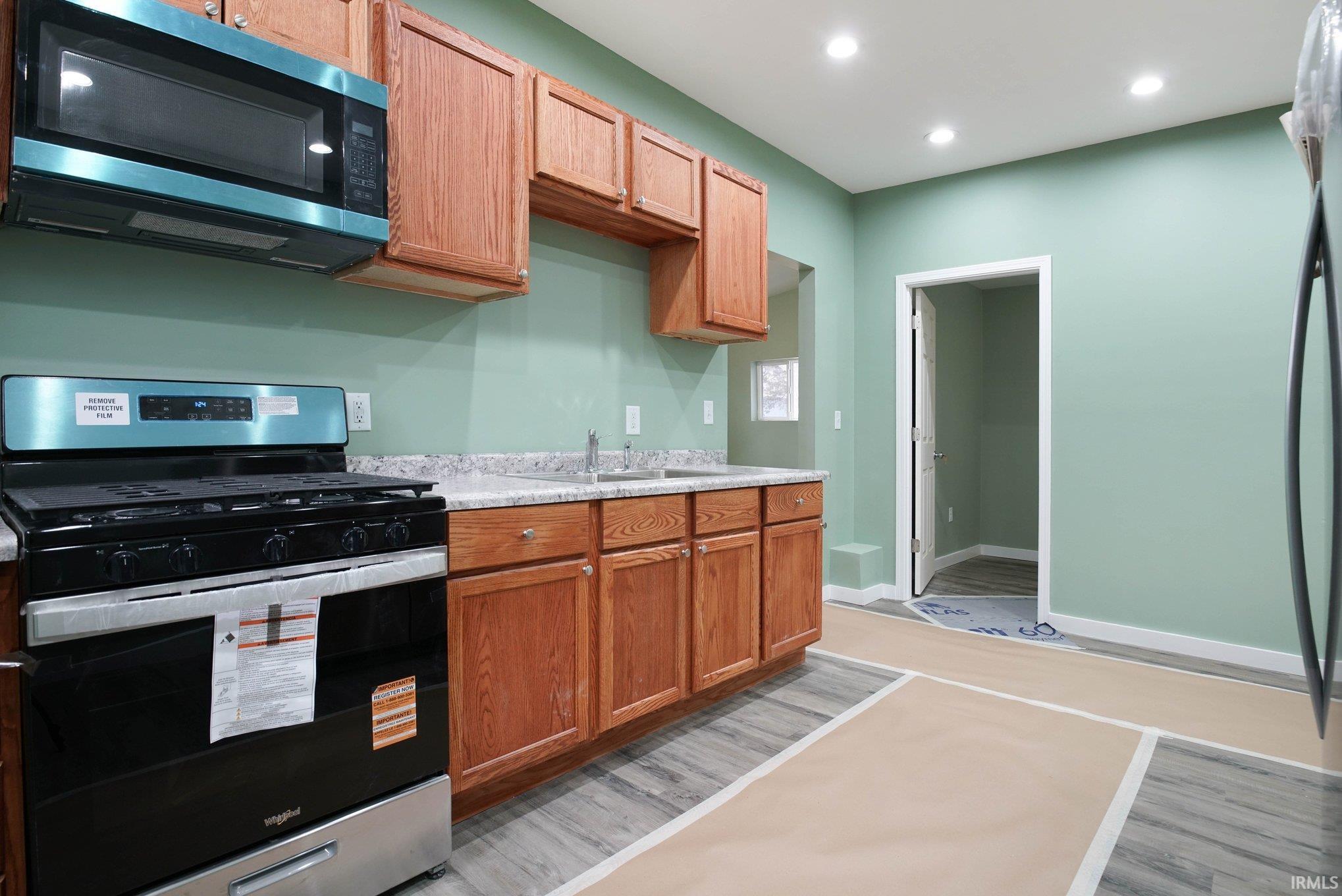 Kitchen with stainless steel appliances, light countertops, light wood-style flooring, recessed lighting, and wood finish cabinets