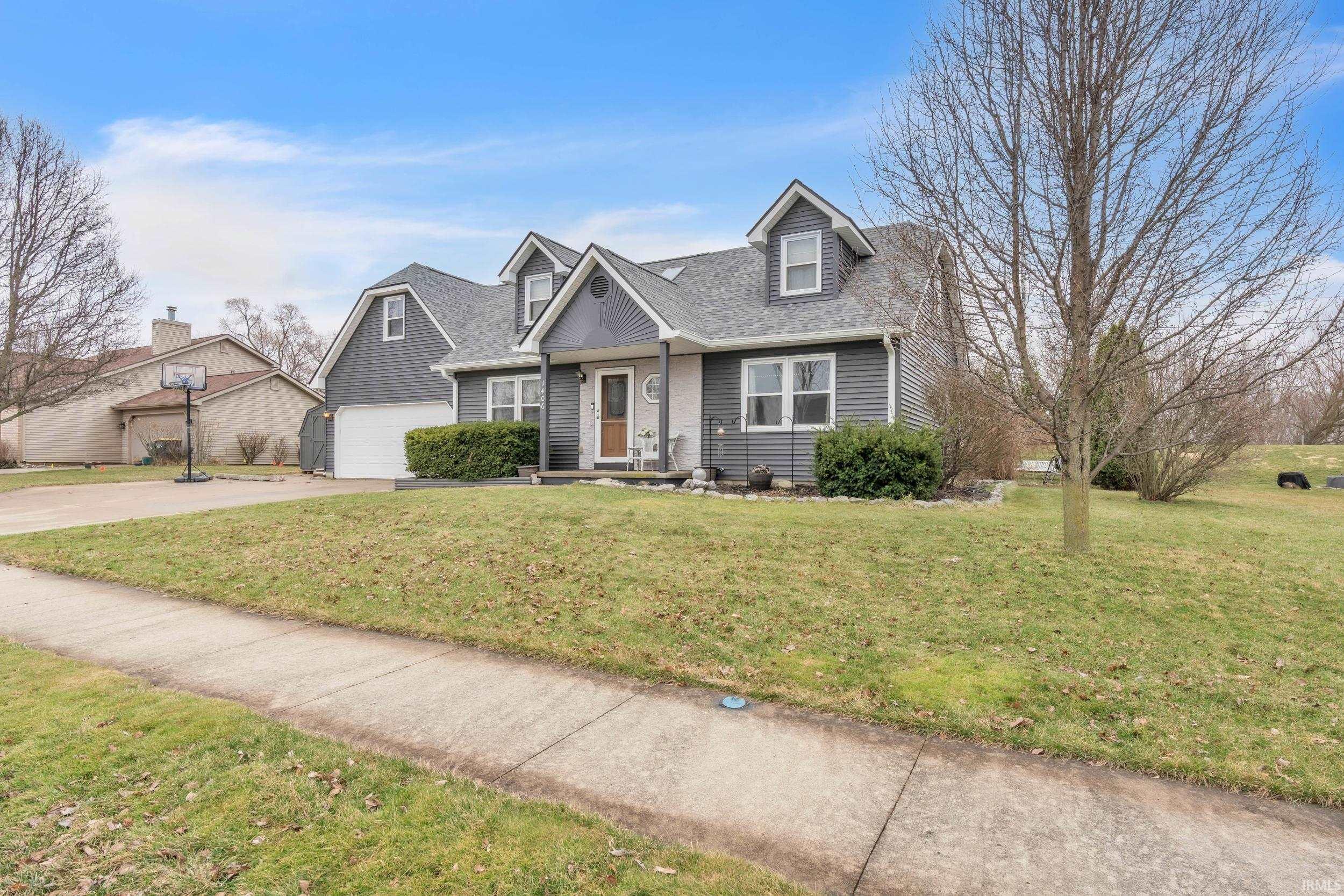 New england style home featuring a front yard, roof with shingles, and concrete driveway