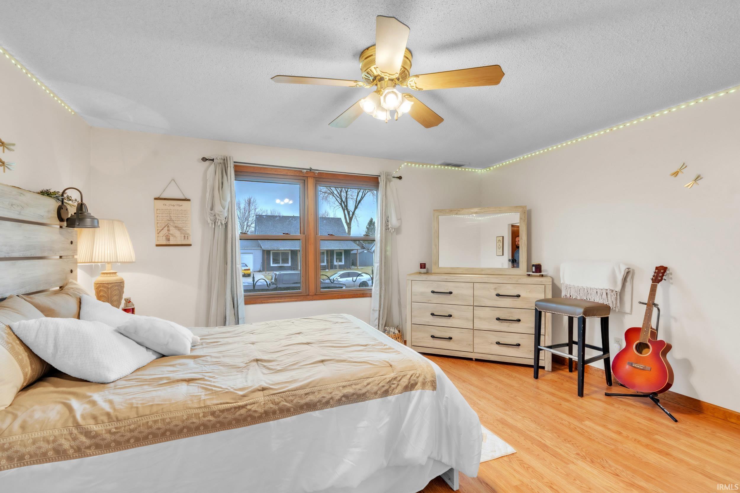 Bedroom featuring a ceiling fan, light wood-type flooring, and a textured ceiling