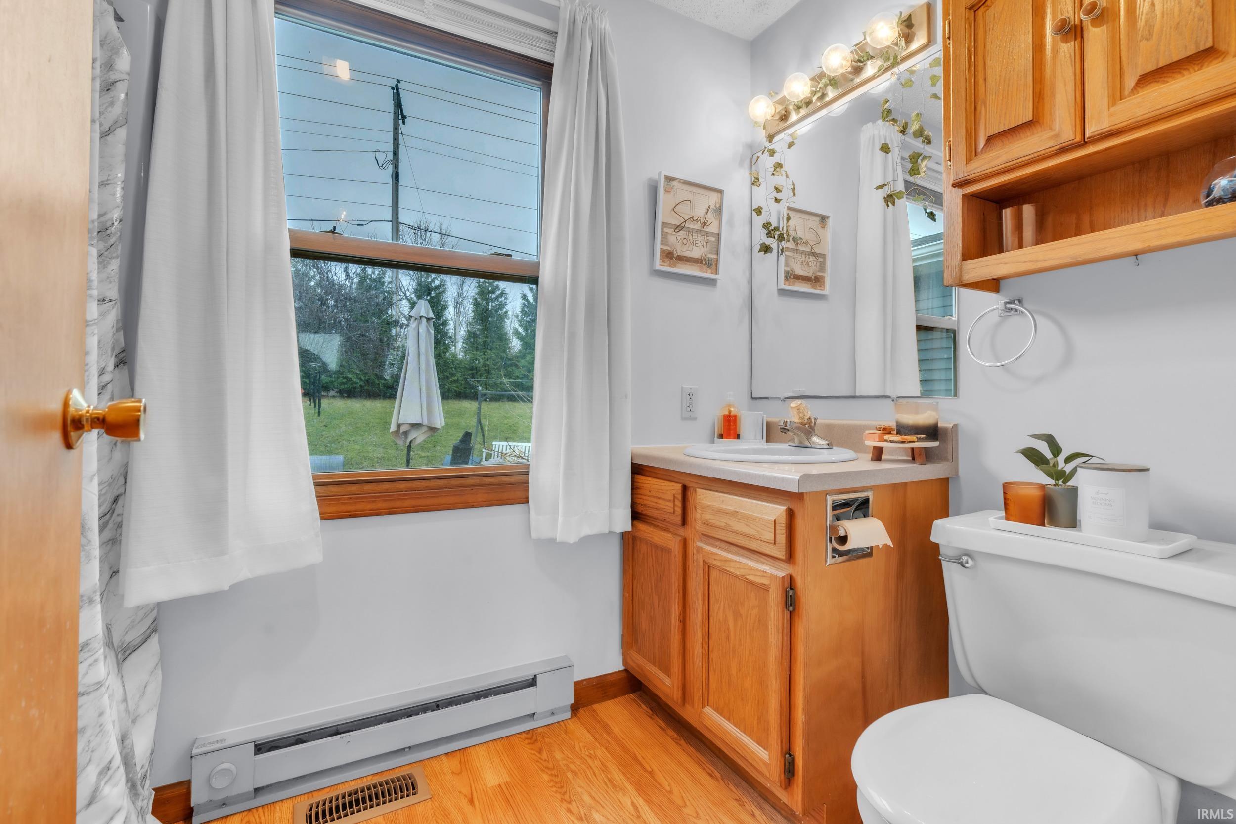 Bathroom featuring baseboard heating, vanity, and light wood-type flooring