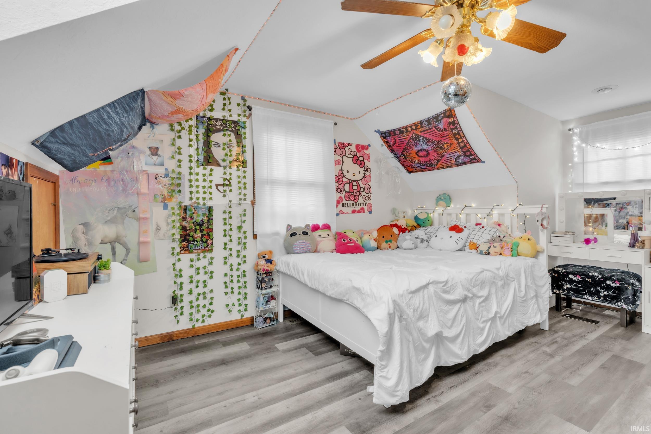 Bedroom with light wood finished floors, ceiling fan, and lofted ceiling