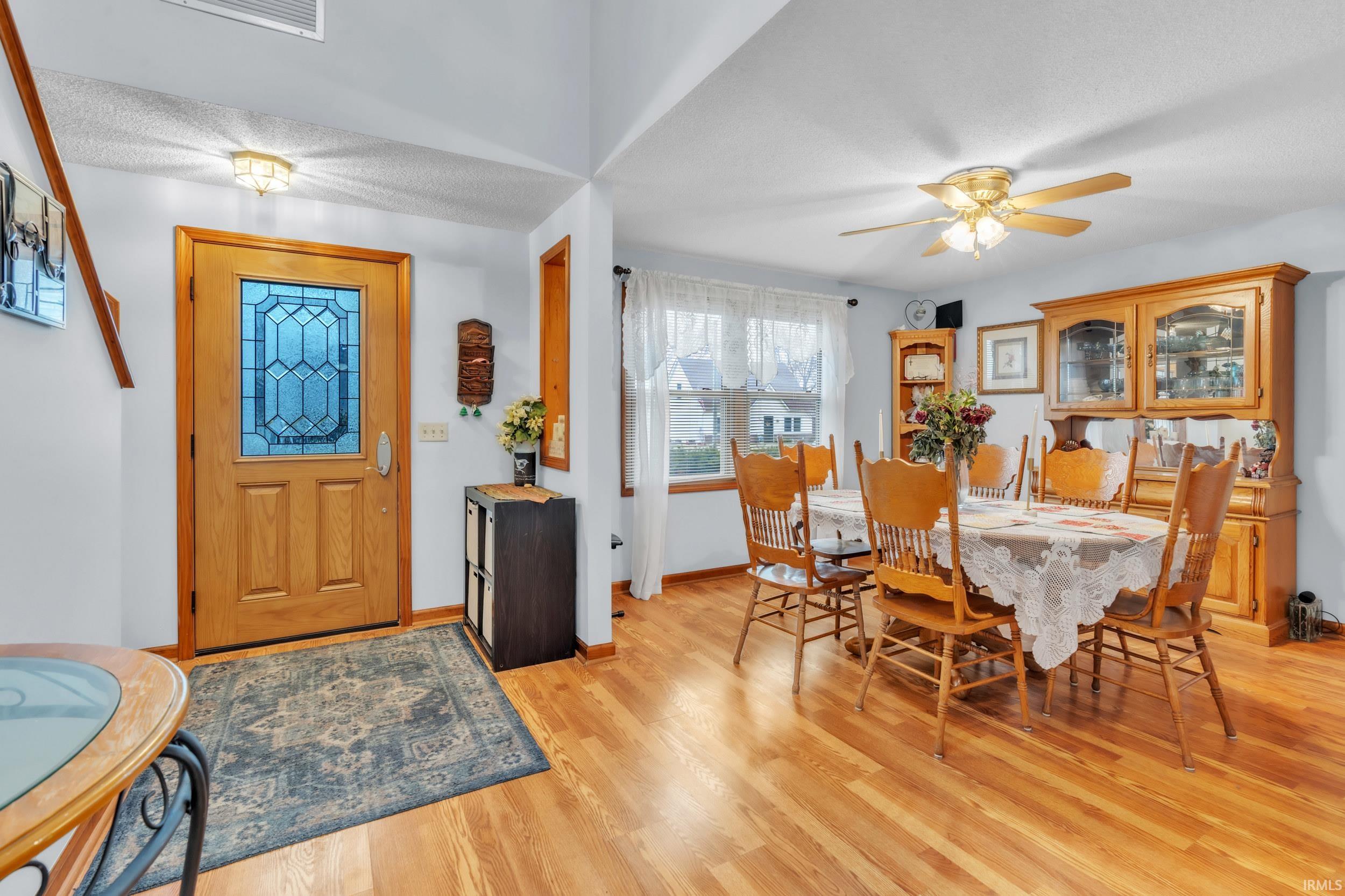 Dining area with light wood finished floors, ceiling fan, and a textured ceiling