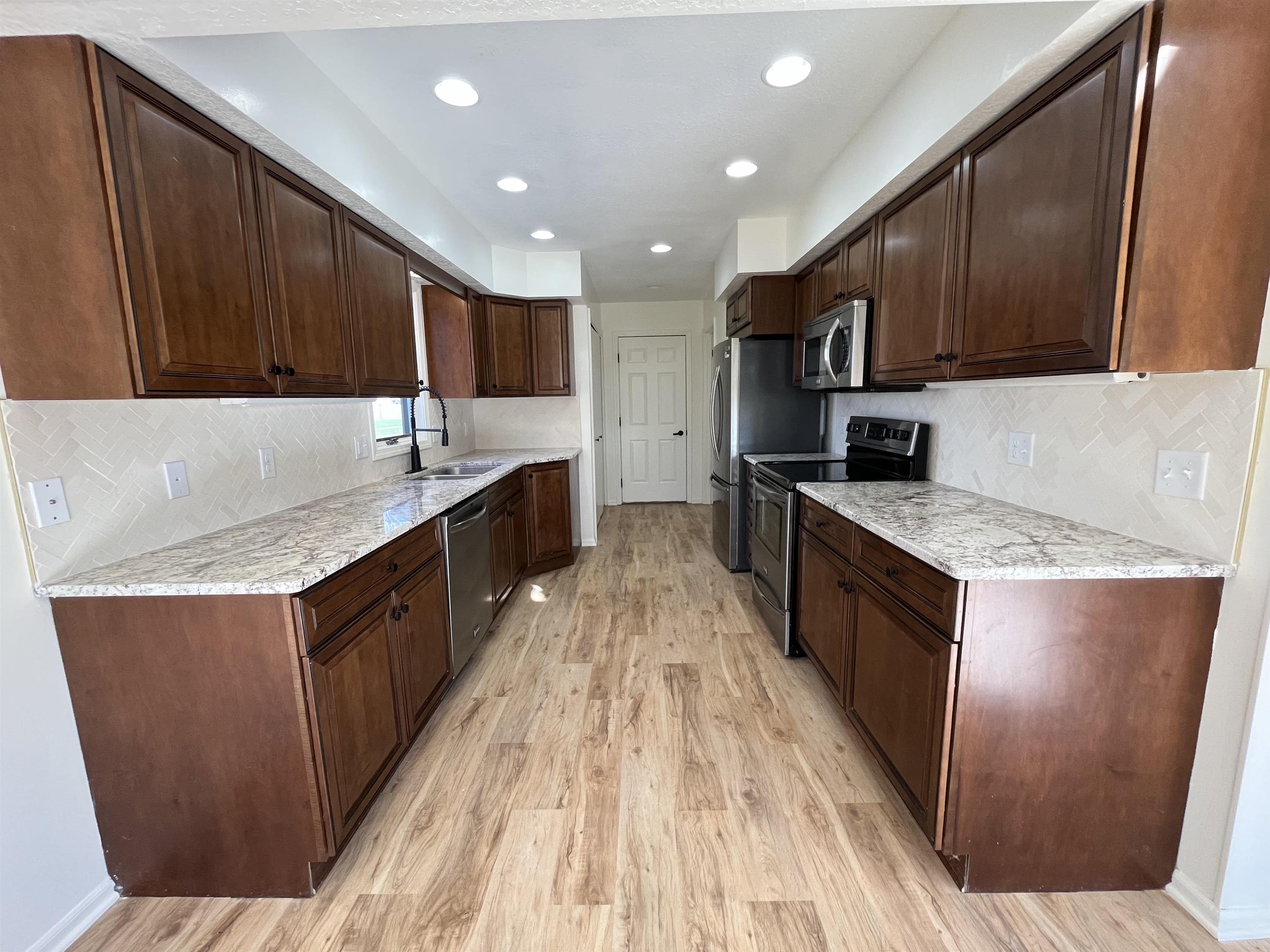 Kitchen featuring stainless steel appliances, tasteful backsplash, recessed lighting, and dark wood finish cabinetry