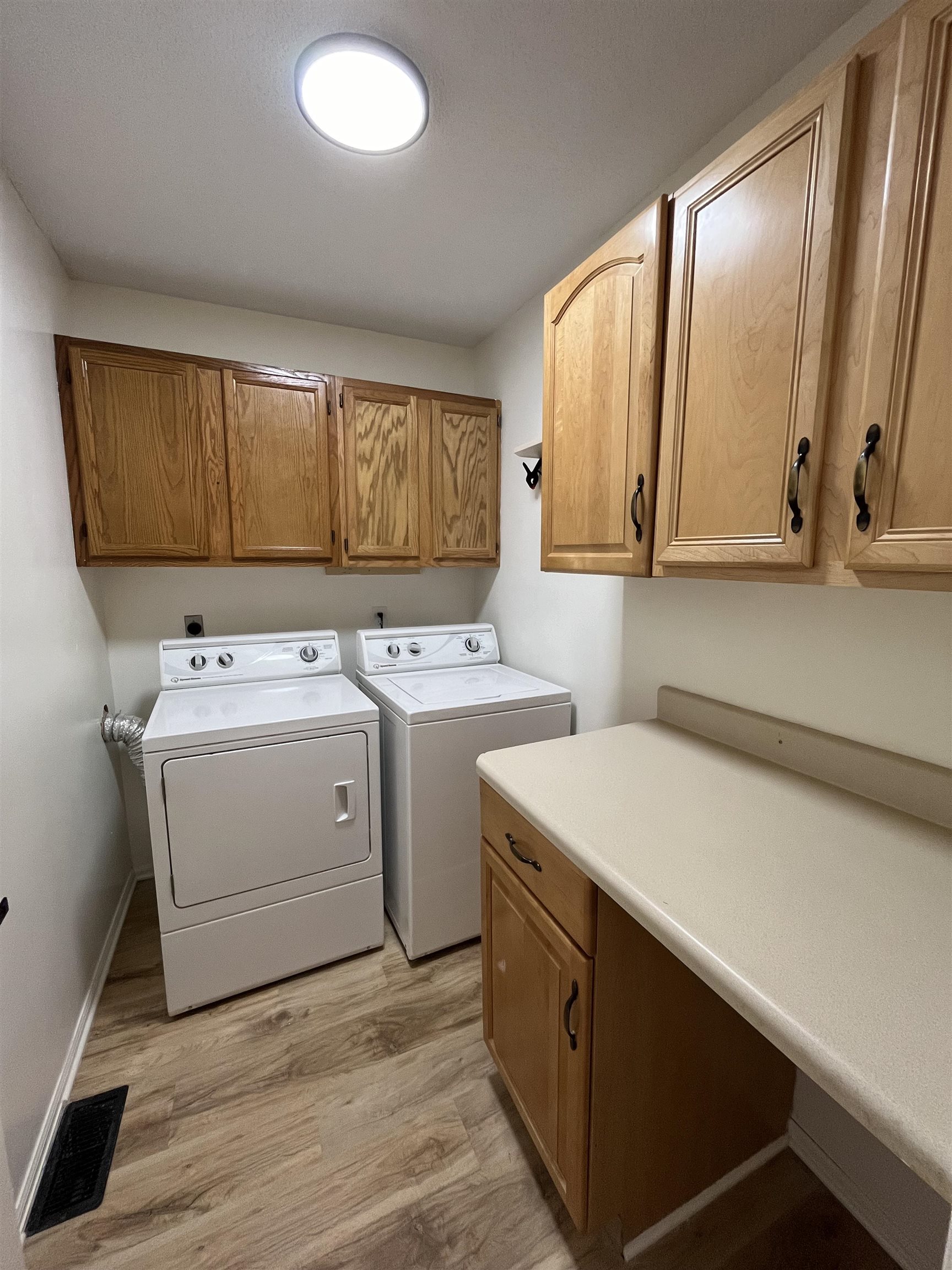 Laundry area featuring light wood-style floors, cabinet space, and independent washer and dryer