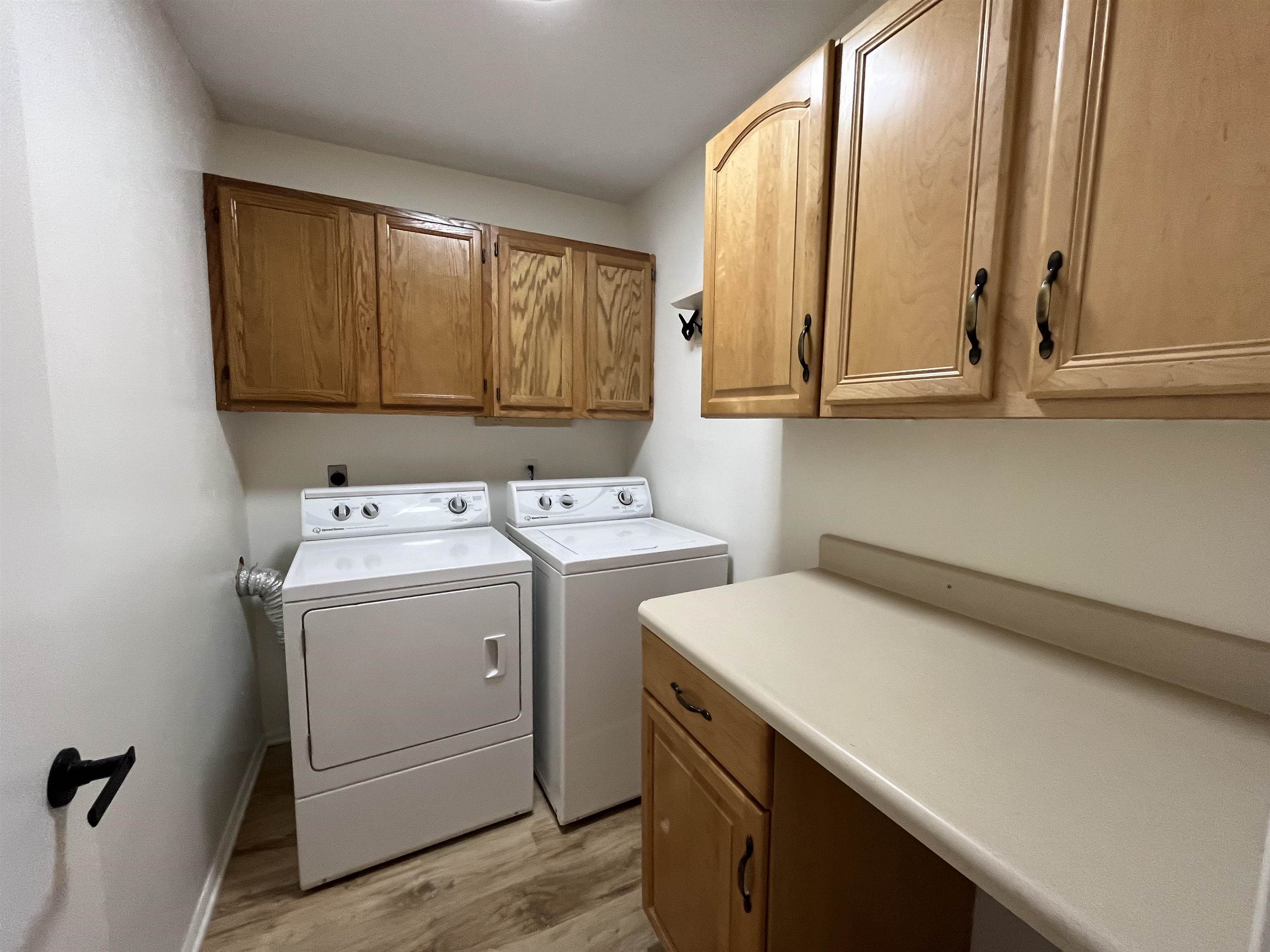 Laundry area featuring light wood-type flooring, cabinet space, and separate washer and dryer