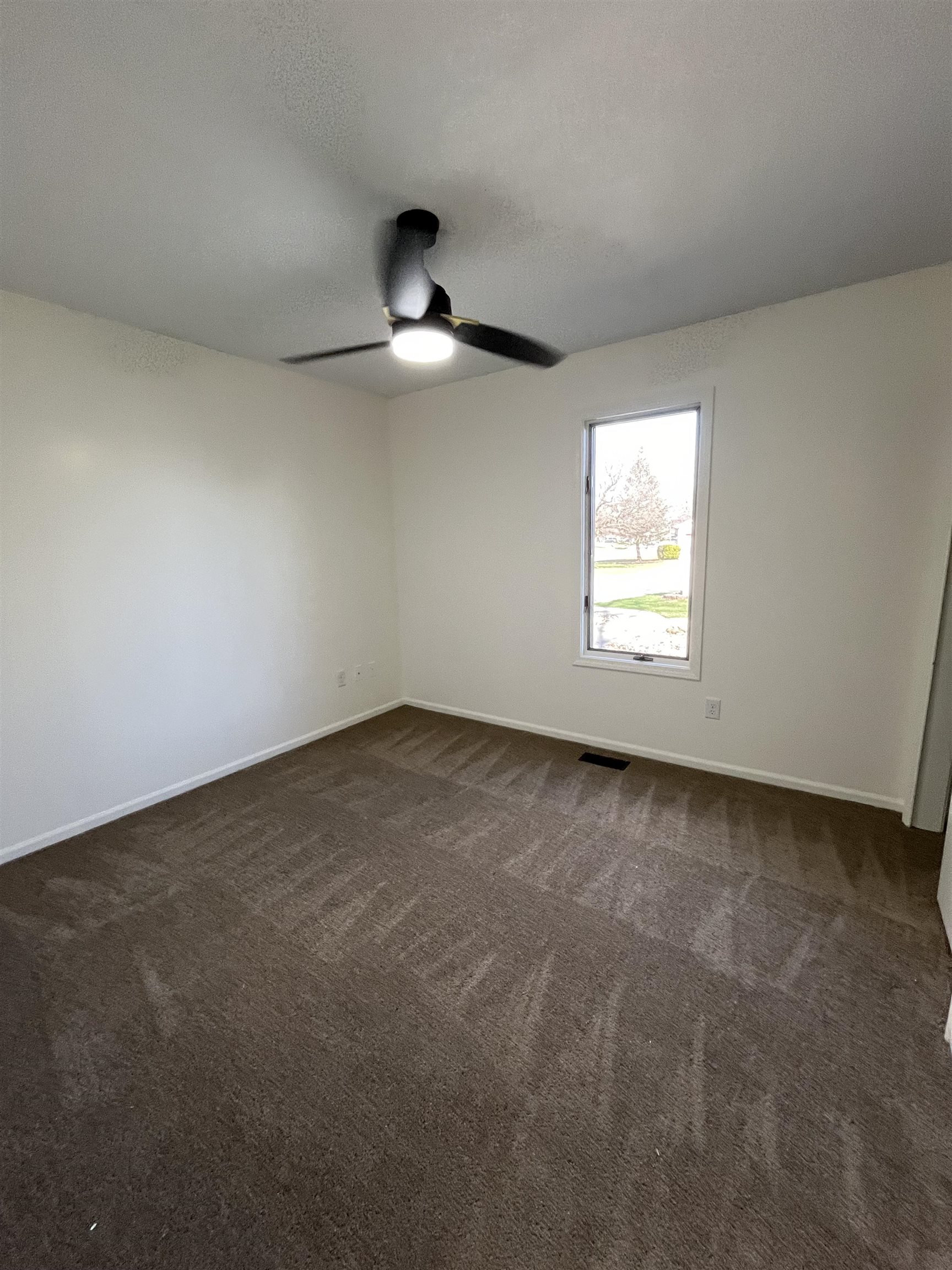 Spare room with dark carpet and ceiling fan