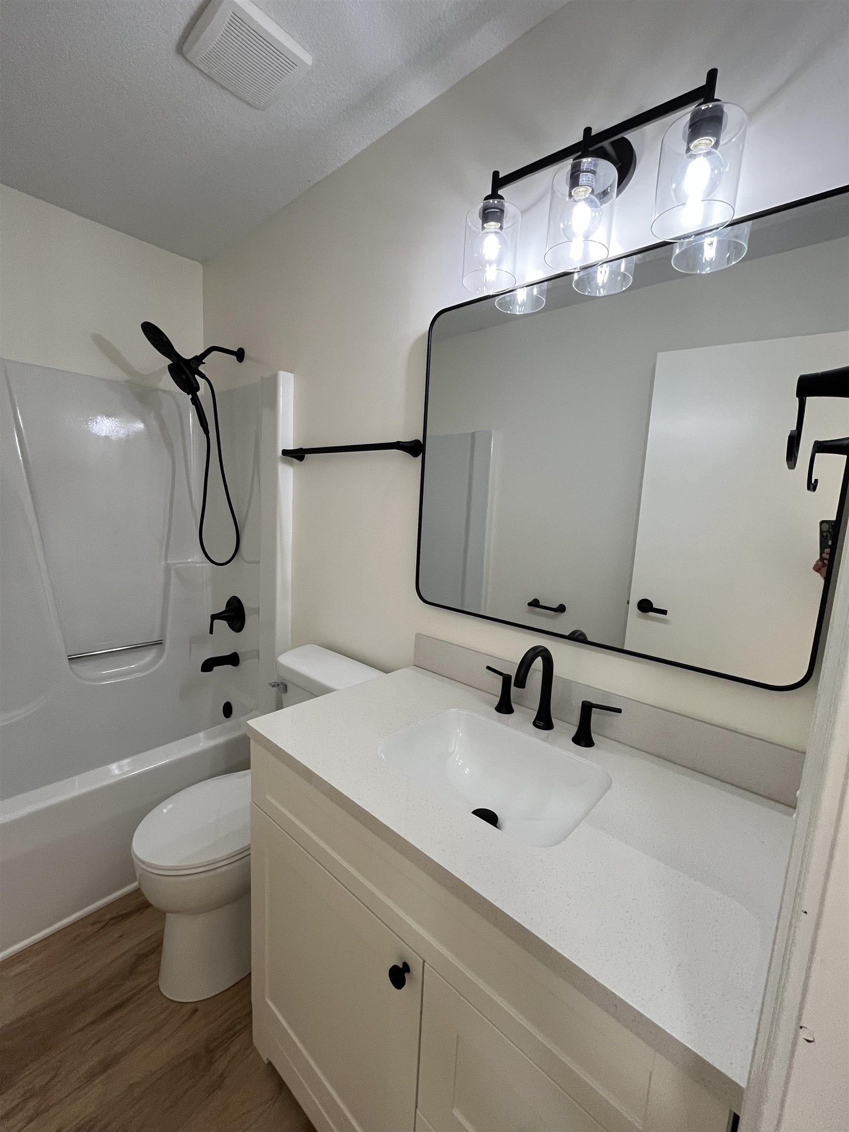 Bathroom with vanity, shower / bath combination, and light wood-style flooring