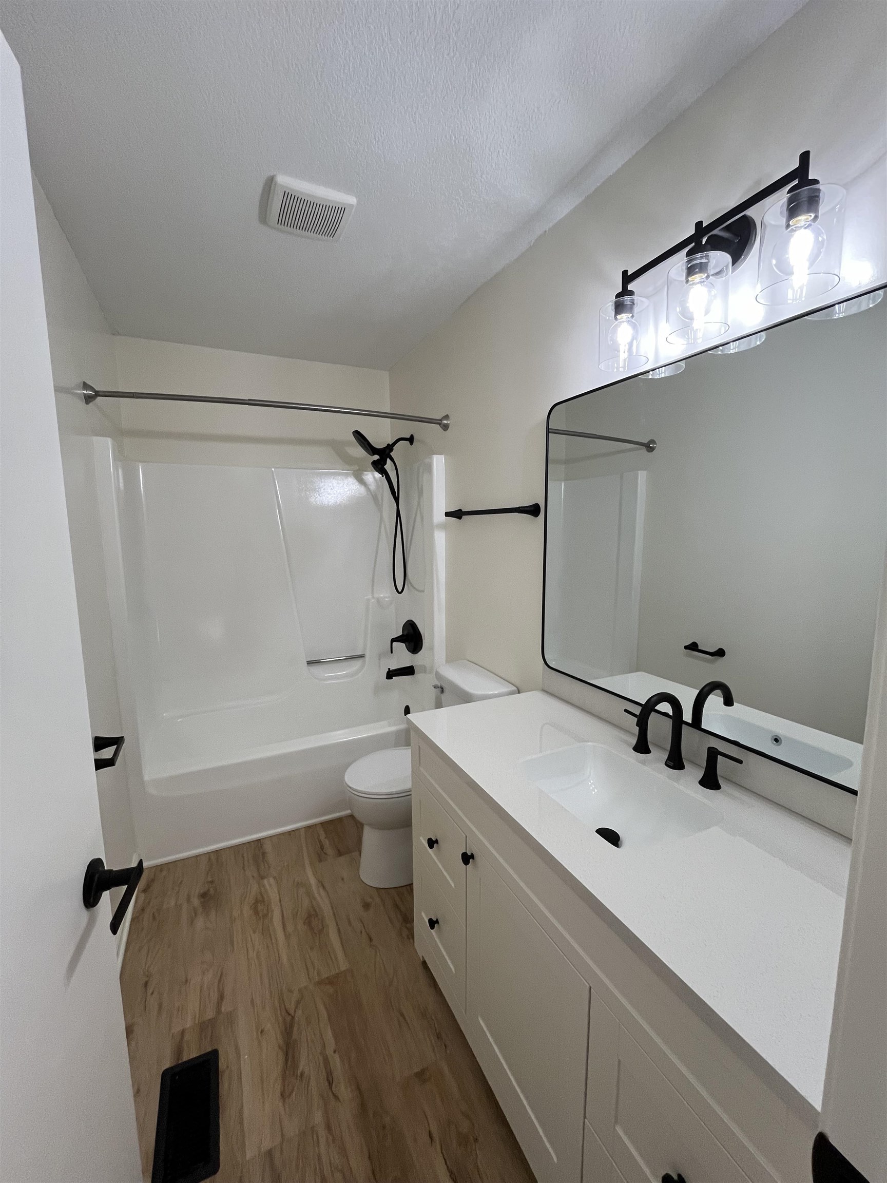 Bathroom featuring vanity, light wood finished floors, shower / bathtub combination, and a textured ceiling