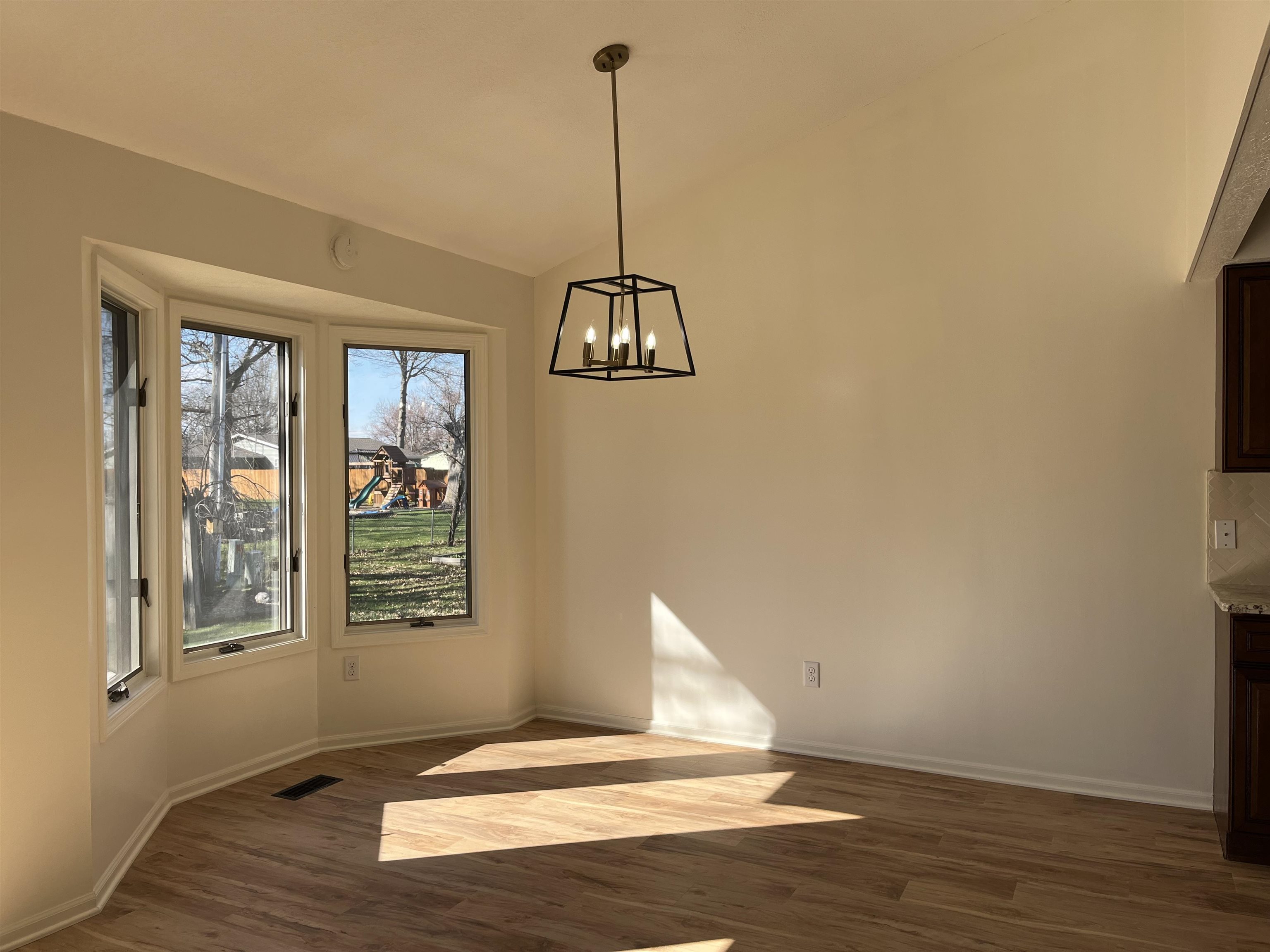 Unfurnished dining area featuring dark wood-type flooring, lofted ceiling, and a chandelier