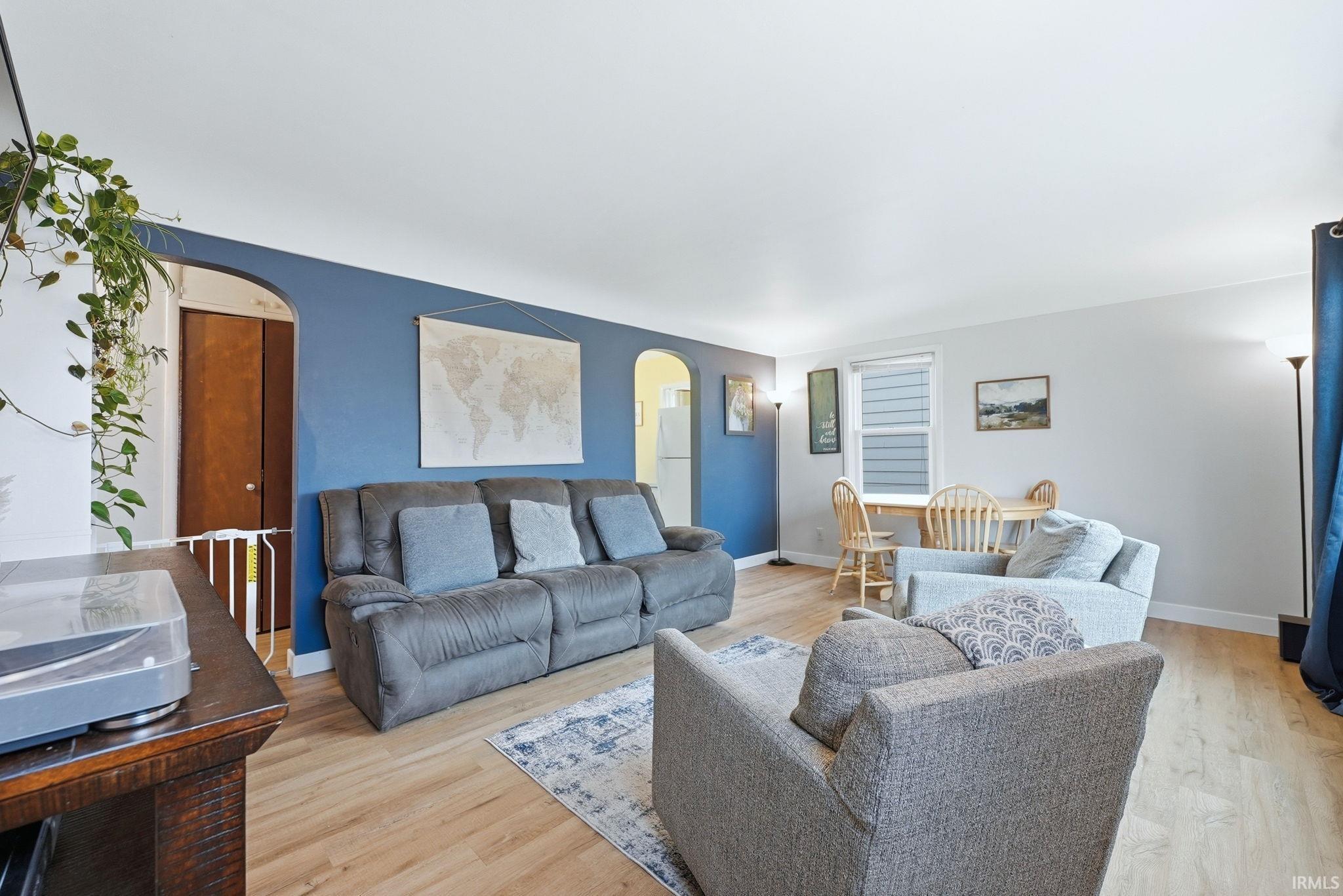 Living room featuring arched walkways and light wood-style floors