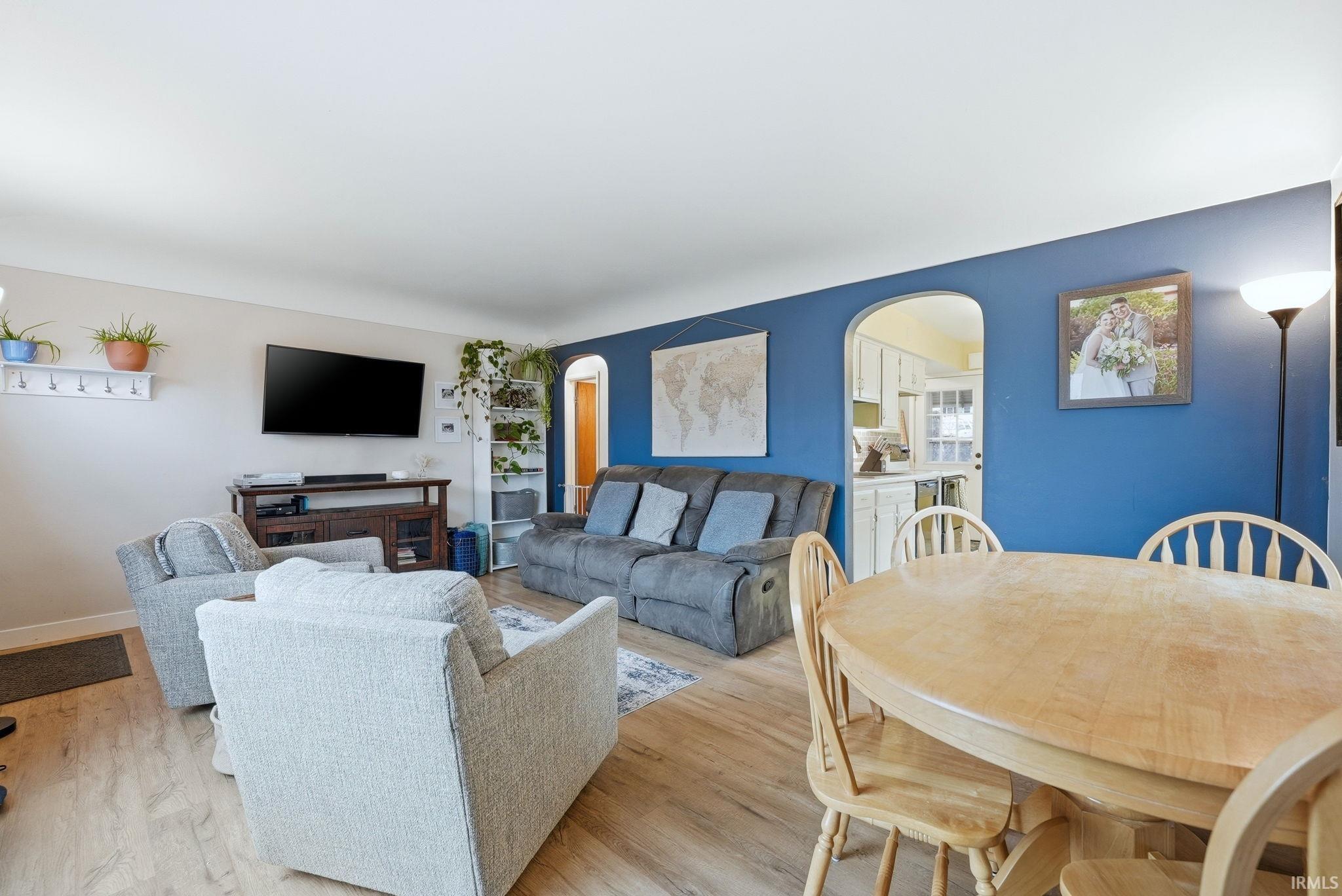 Living area with arched walkways and light wood finished floors