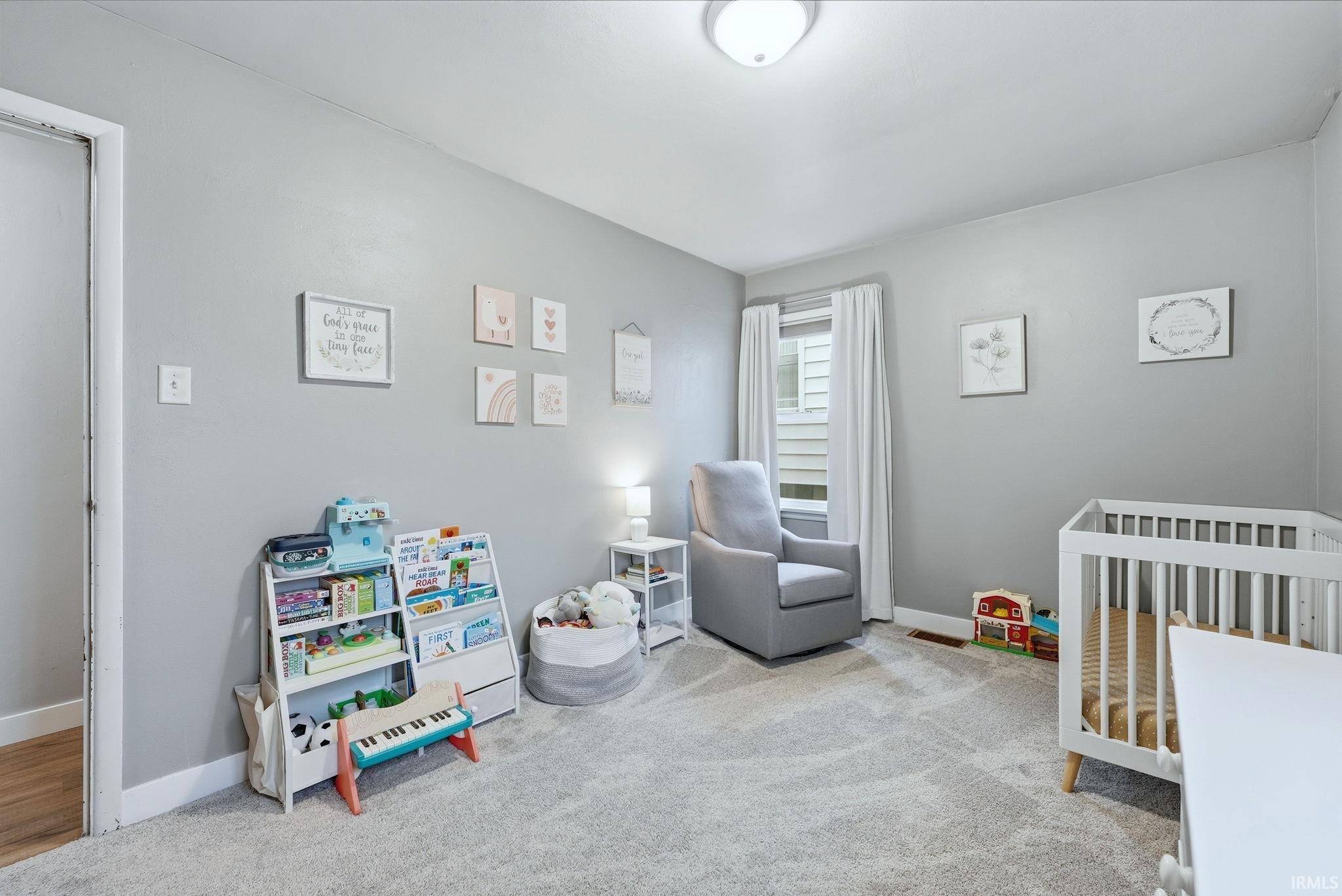 Bedroom with a nursery area and light carpet