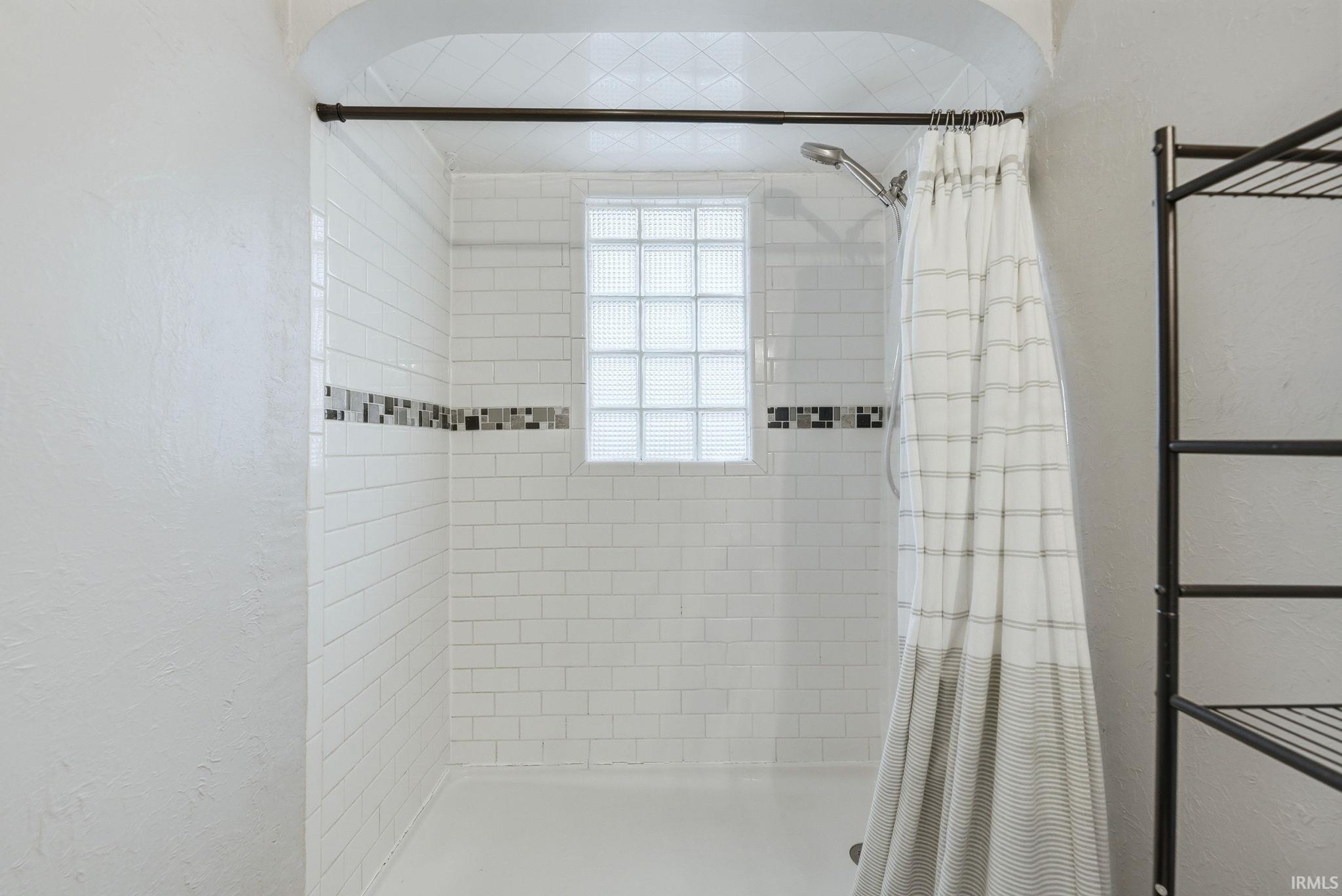 Bathroom featuring a textured wall and a stall shower