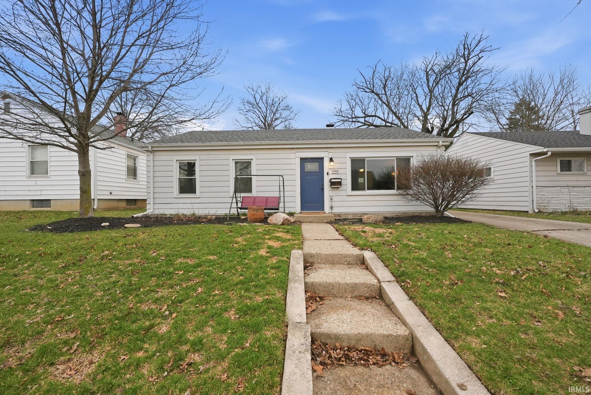 View of front of house with a front lawn and roof with shingles