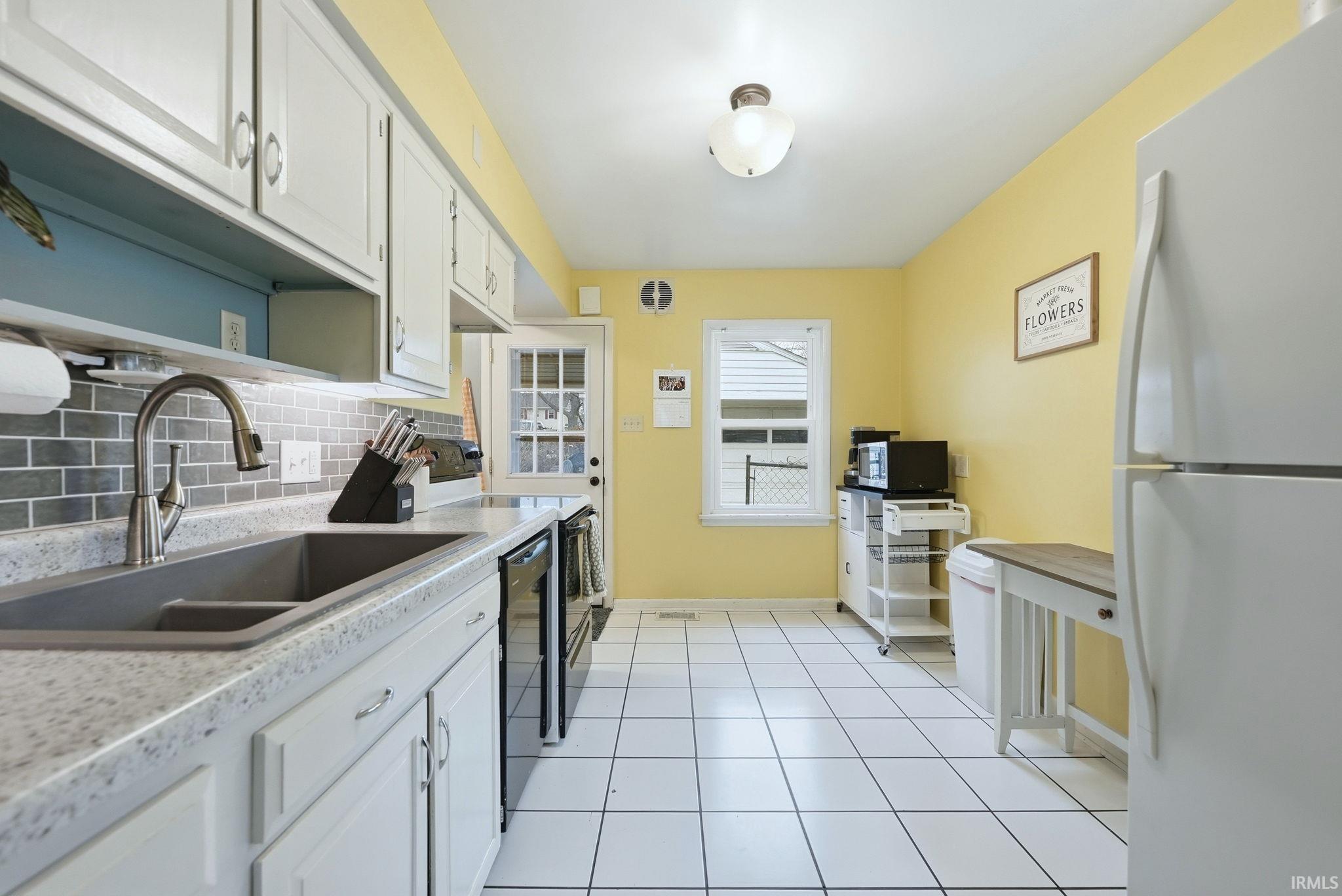 Kitchen featuring black appliances, light countertops, white cabinetry, open shelves, and tasteful backsplash