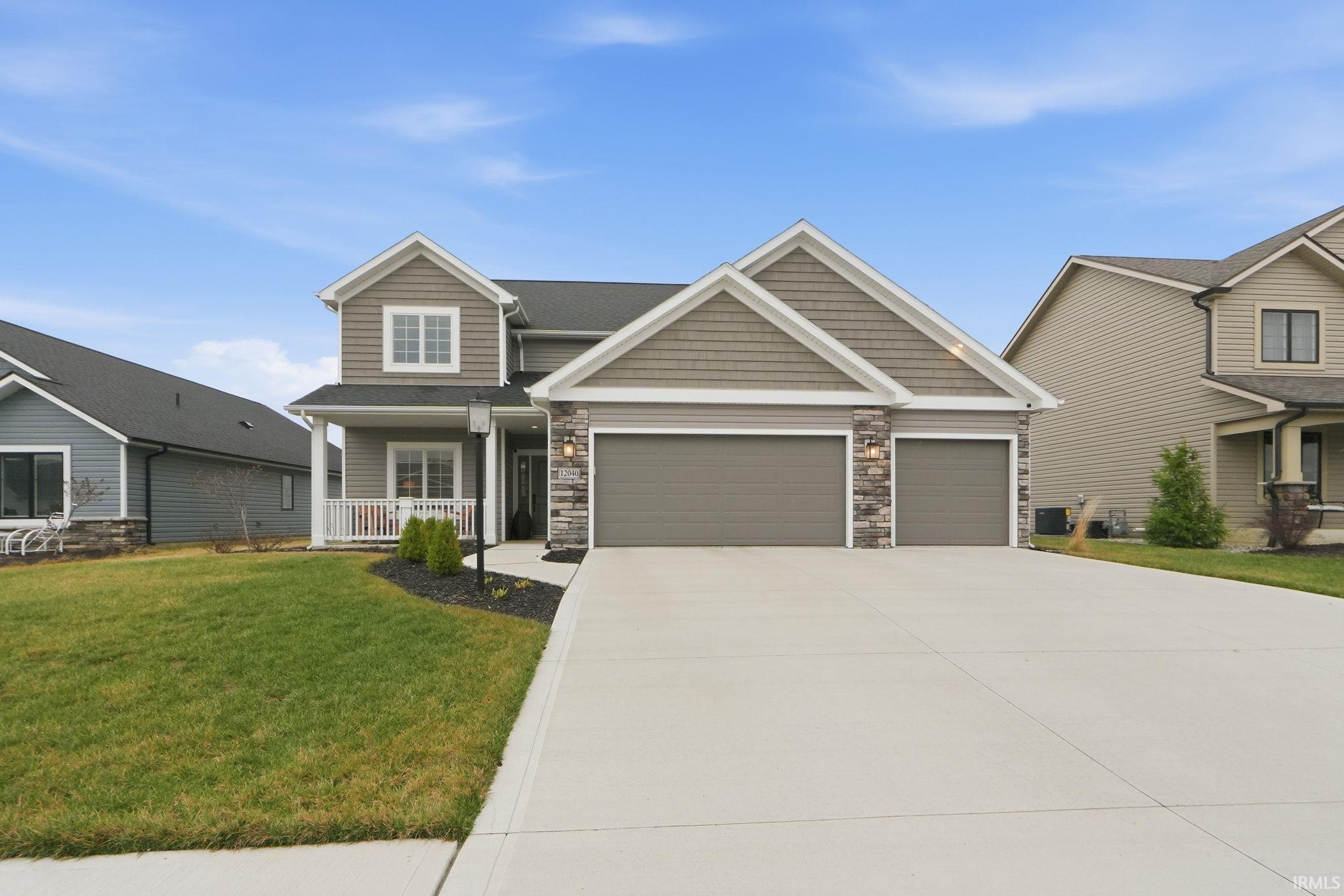 Craftsman house featuring a front yard, covered porch, an attached garage, stone siding, and concrete driveway