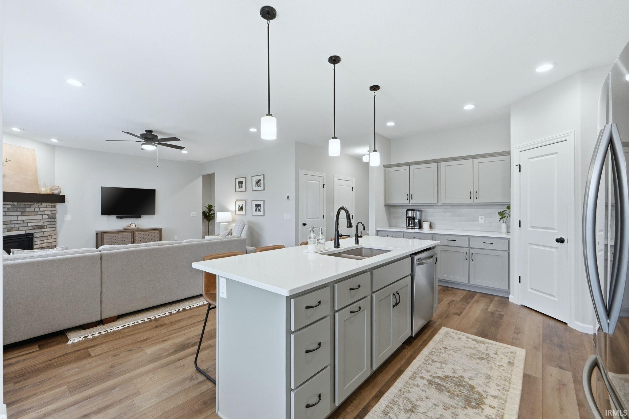 Kitchen featuring gray cabinetry, a kitchen island with sink, a breakfast bar area, and stainless steel appliances