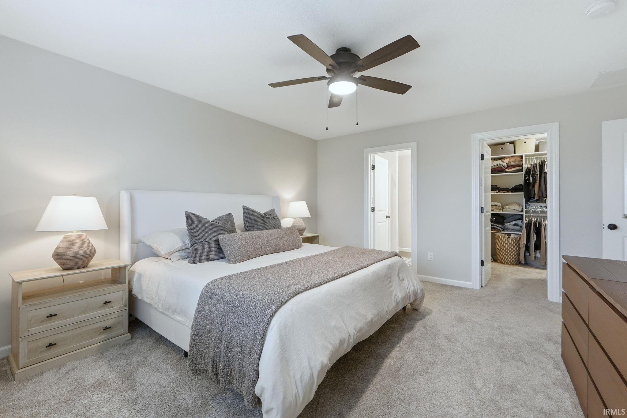 Bedroom featuring a walk in closet, light carpet, and ceiling fan
