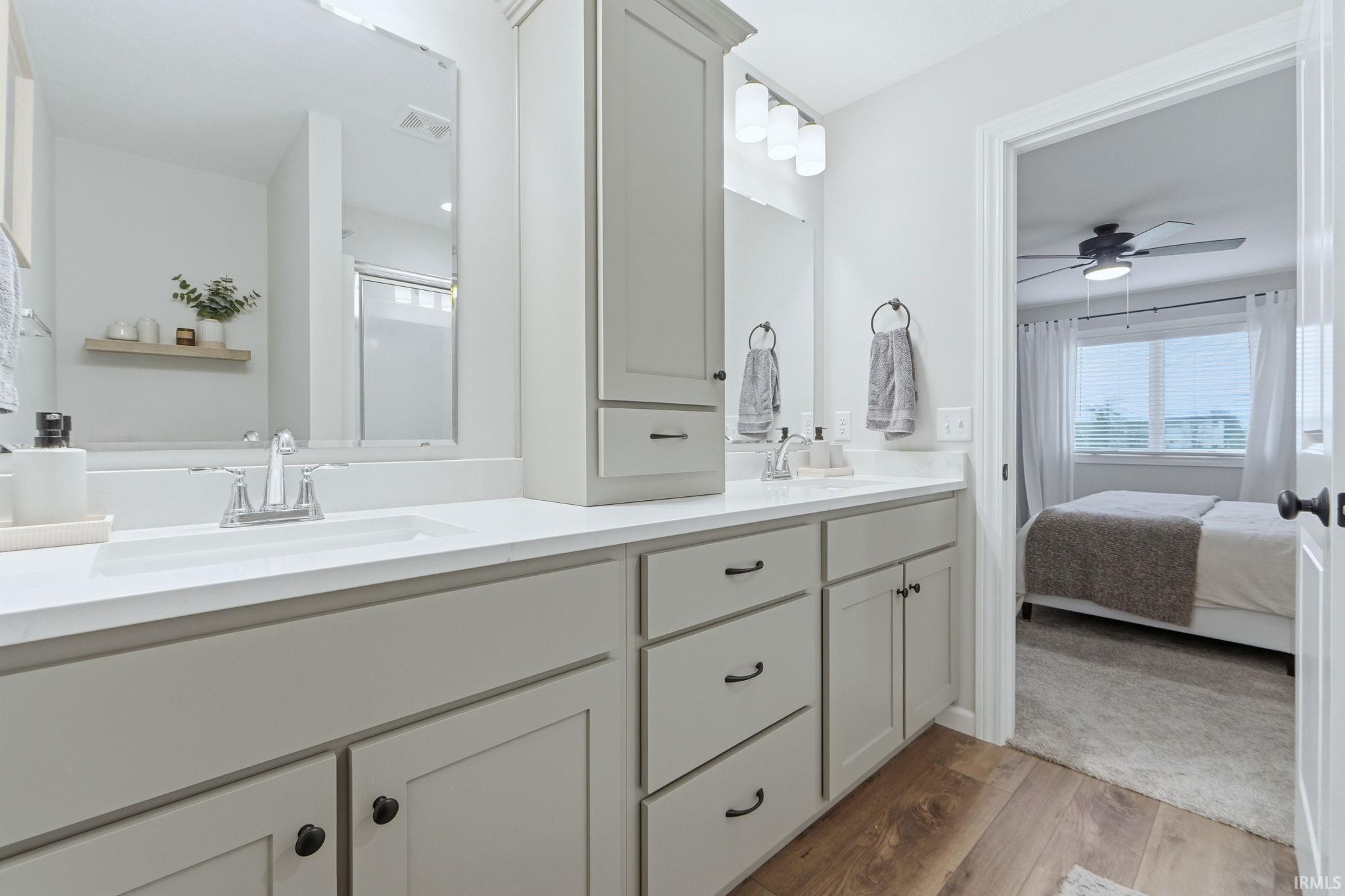 Full bath with double vanity, ensuite bath, light wood-type flooring, a stall shower, and ceiling fan