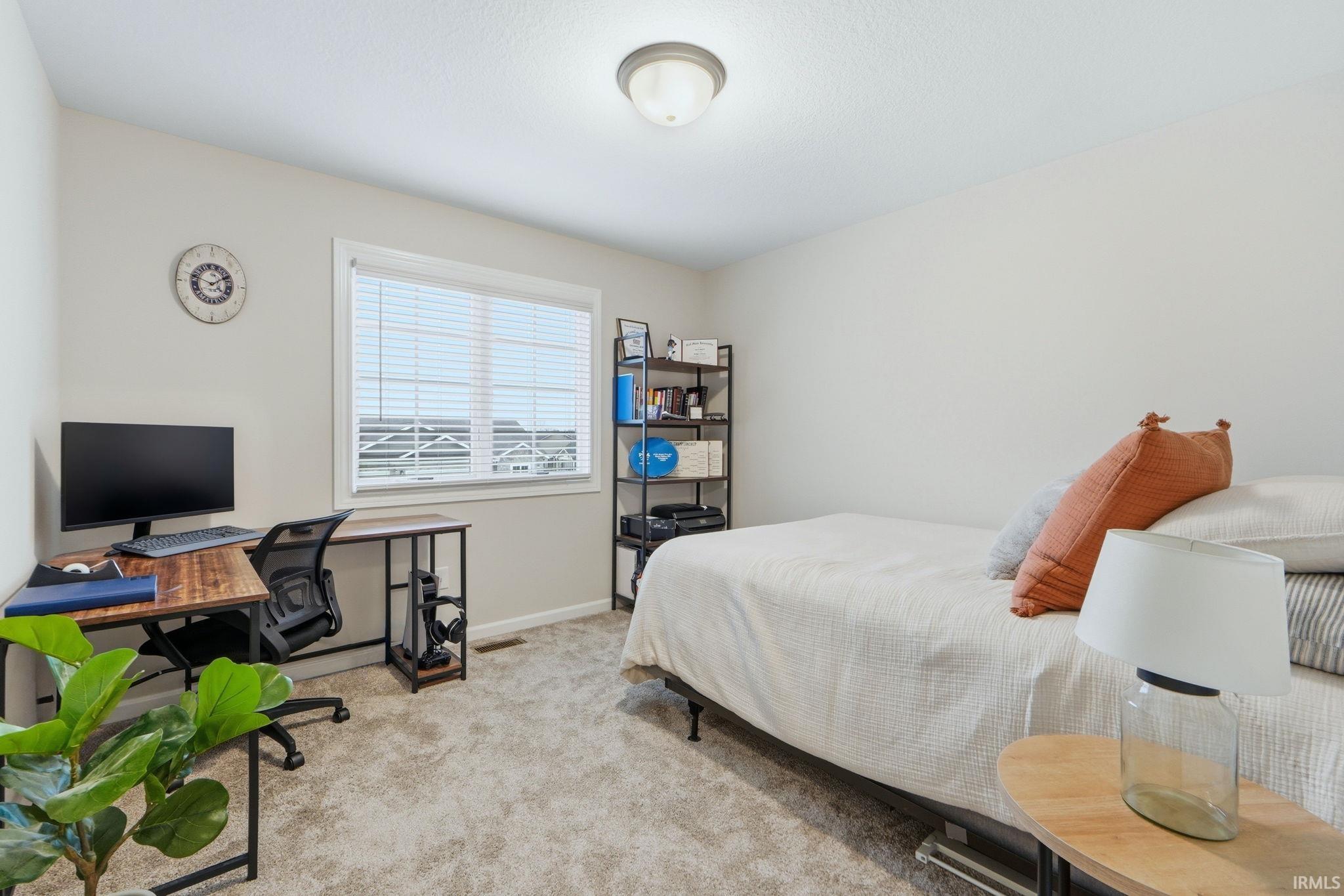 Bedroom with light colored carpet and a desk