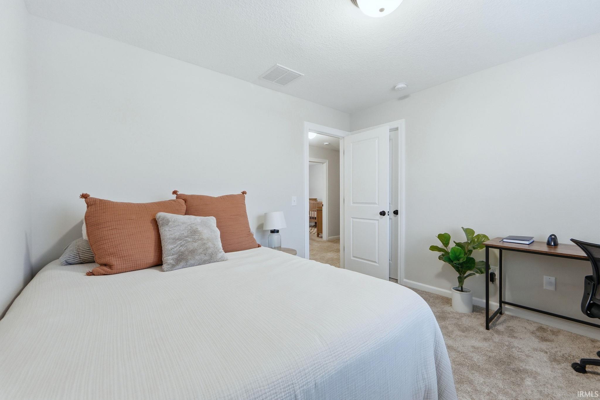 Bedroom with light colored carpet and baseboards