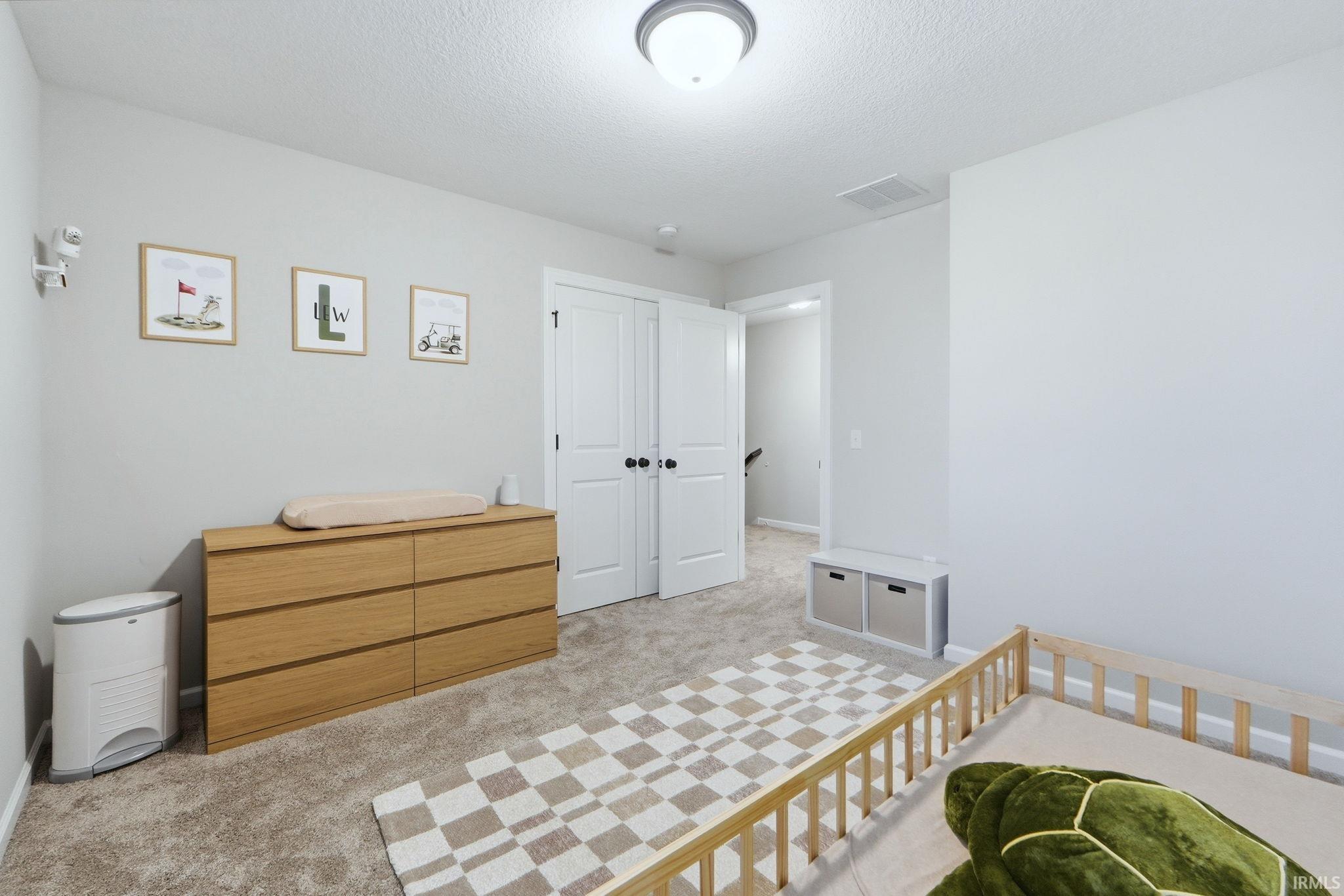 Bedroom featuring light carpet, a closet, and a textured ceiling
