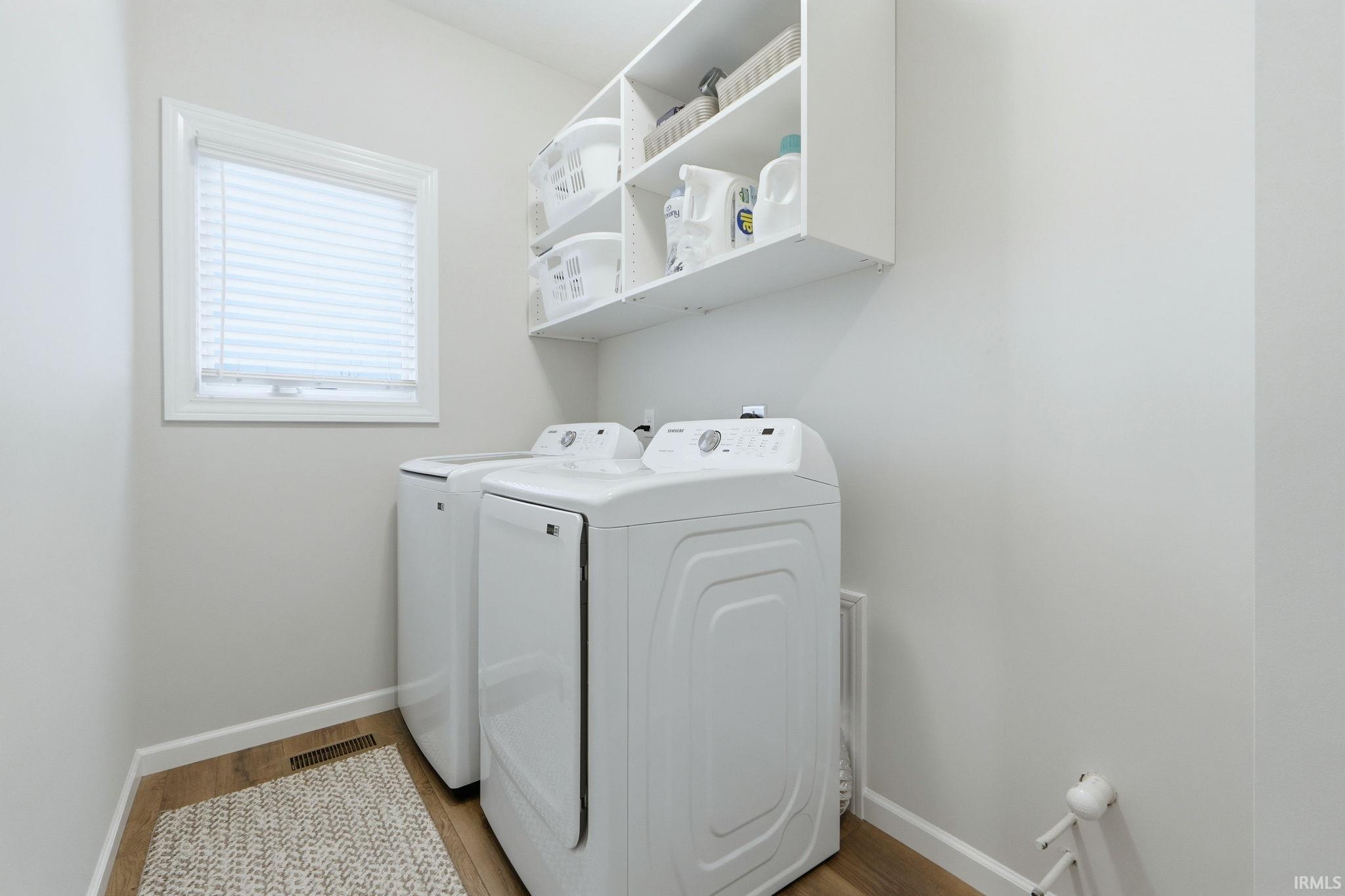 Laundry area with washer and clothes dryer and light wood-type flooring