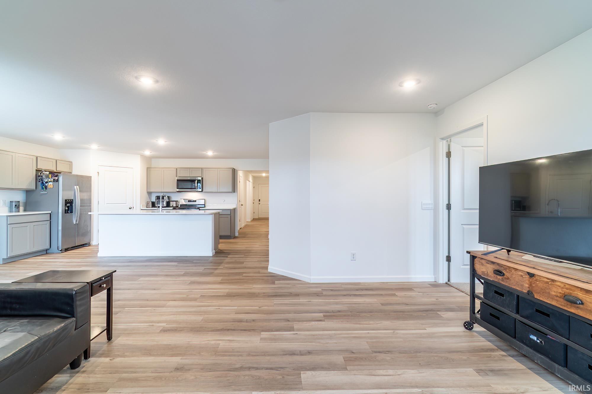 Living area with light wood-style flooring and recessed lighting