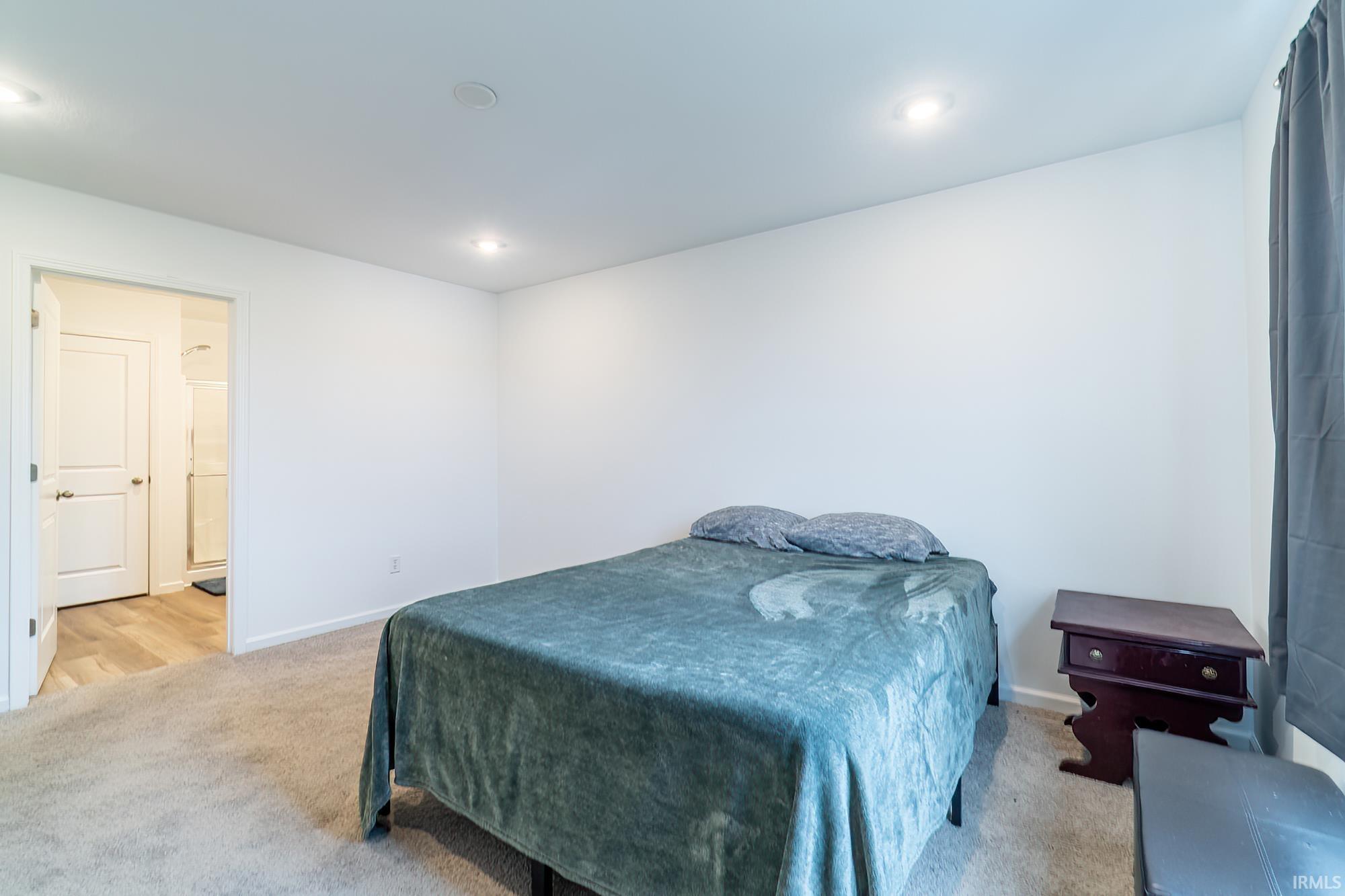 Bedroom with light carpet, recessed lighting, and ensuite bath